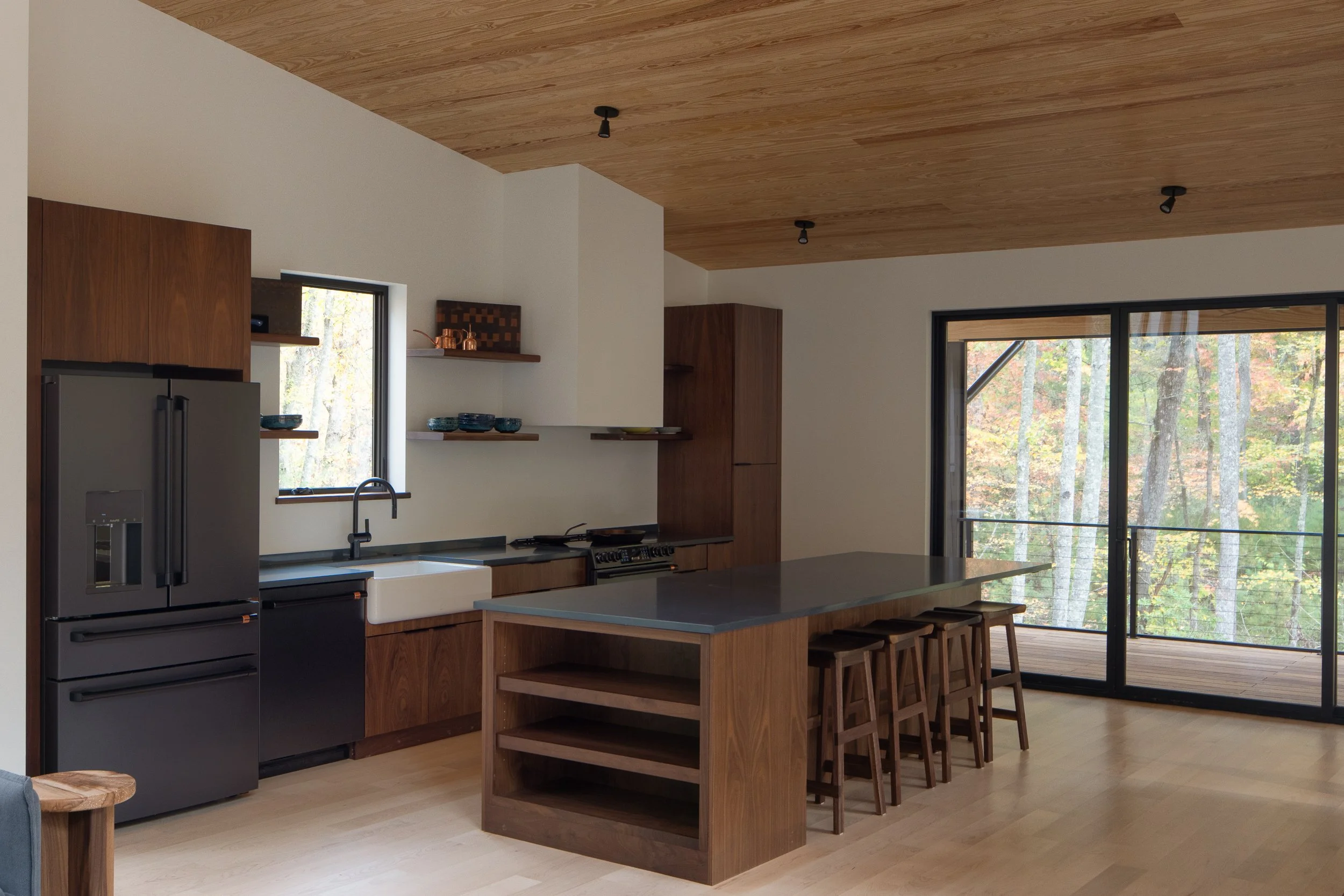 Kitchen island and sliding glass doors opening toward a deck and surrounding trees.