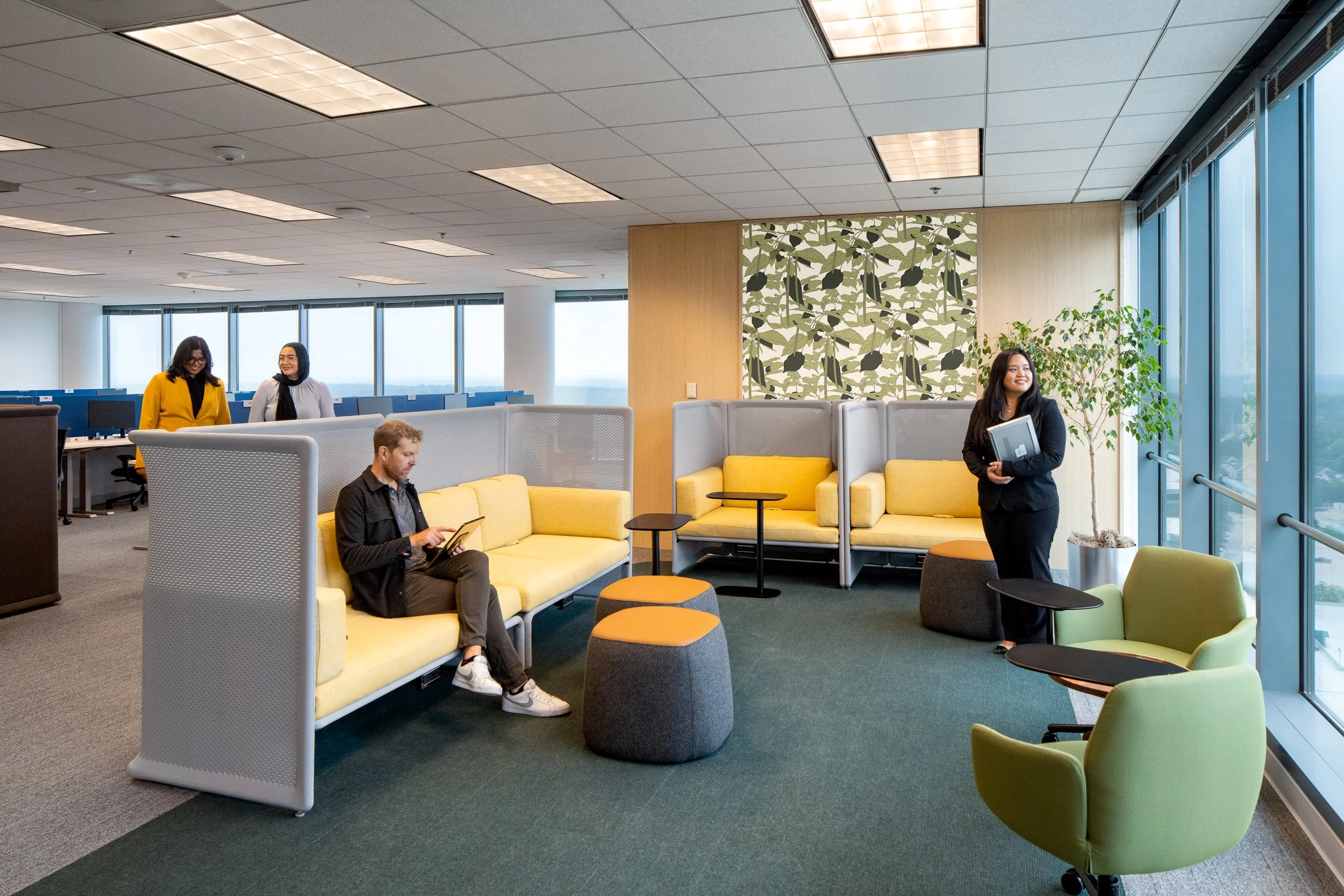 Modern office seating area with bright yellow couches and city view.
