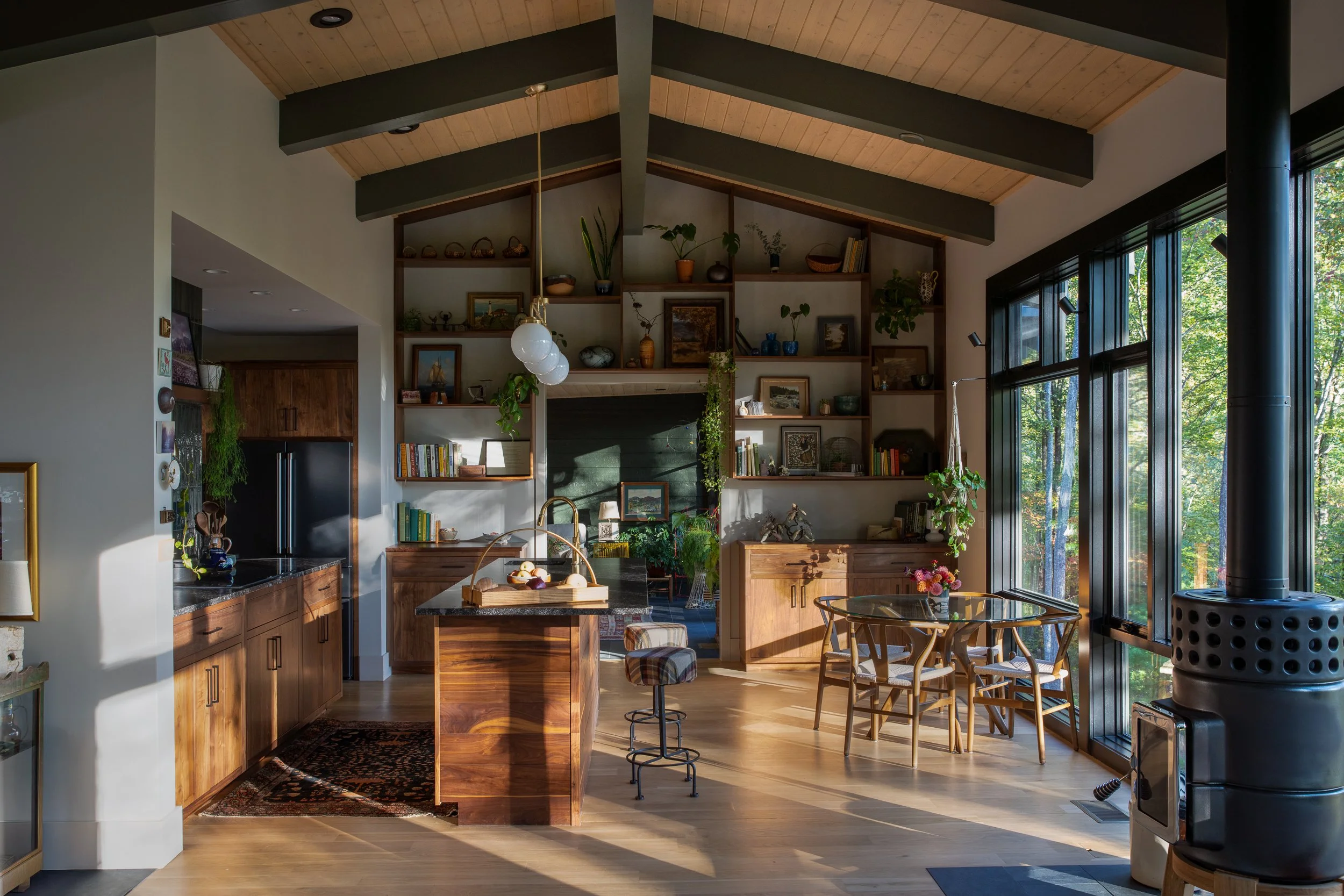 Open living and dining area with vaulted wood ceiling, large windows, and warm afternoon light.