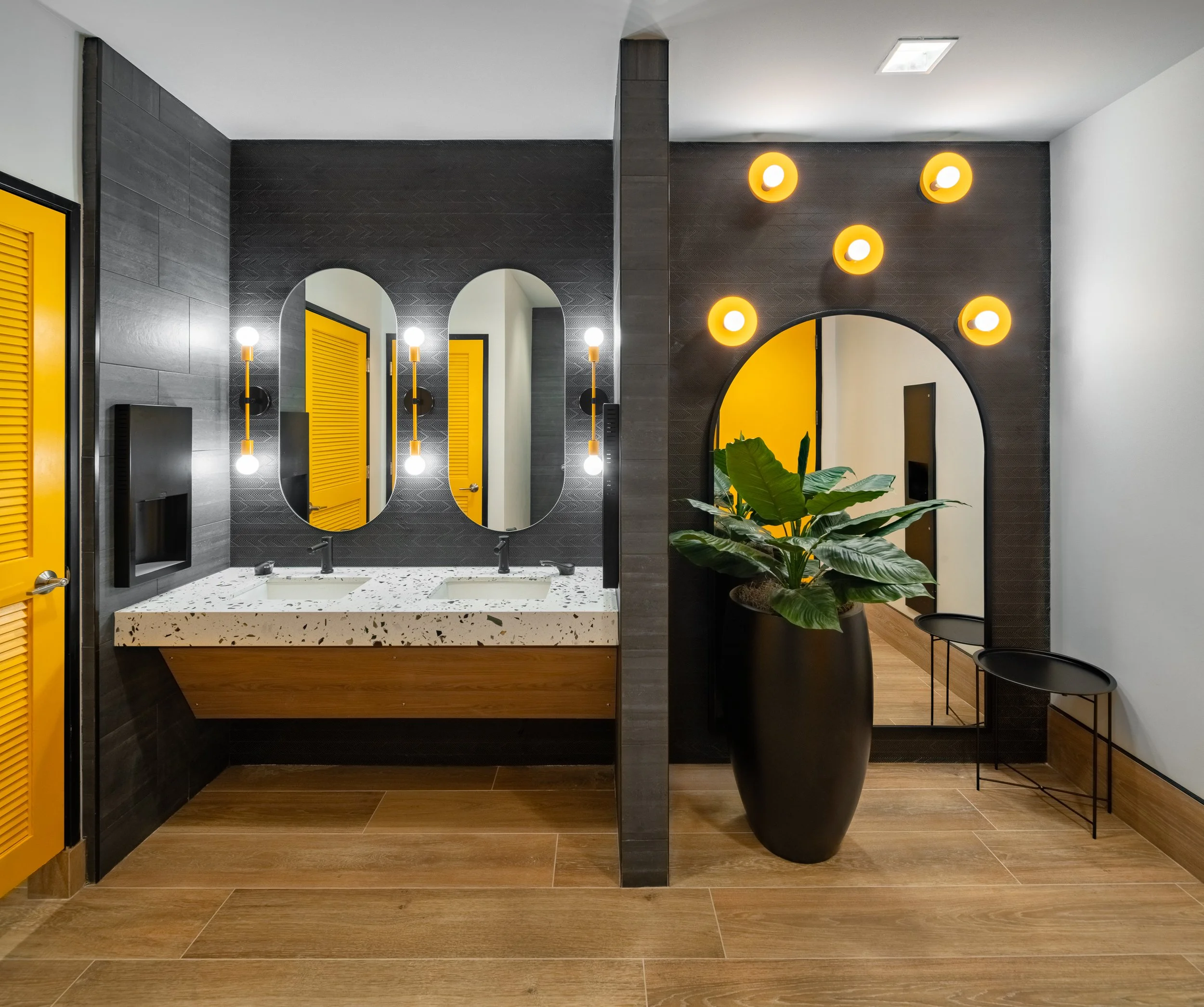 Contemporary restroom with black walls, yellow doors, and stylish lighting.