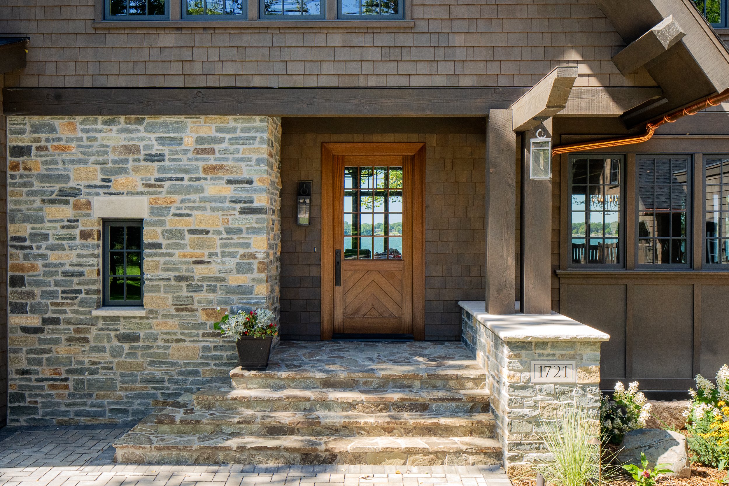 Stone entryway with wooden door and stairs leading to front porch.
