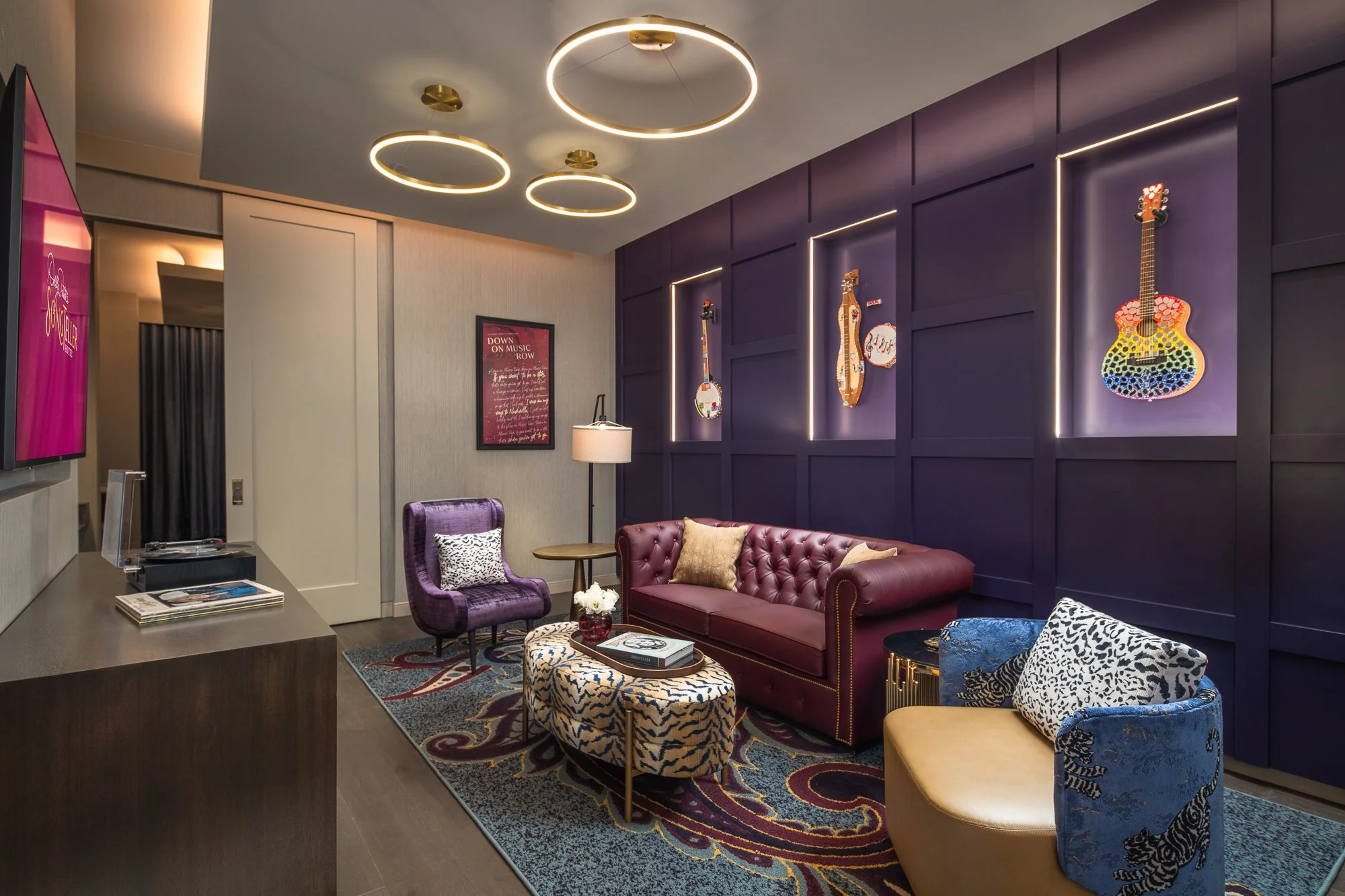 The Acoustic Suite at SongTeller Hotel with illuminated instrument displays, leather sofa, patterned seating, and circular ceiling lights.