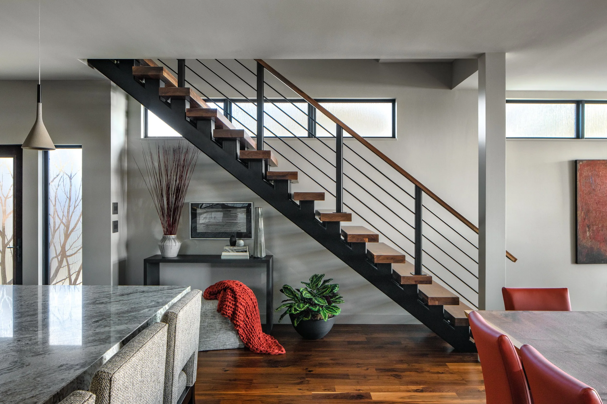 Floating staircase with wooden steps and black railing in a modern home.
