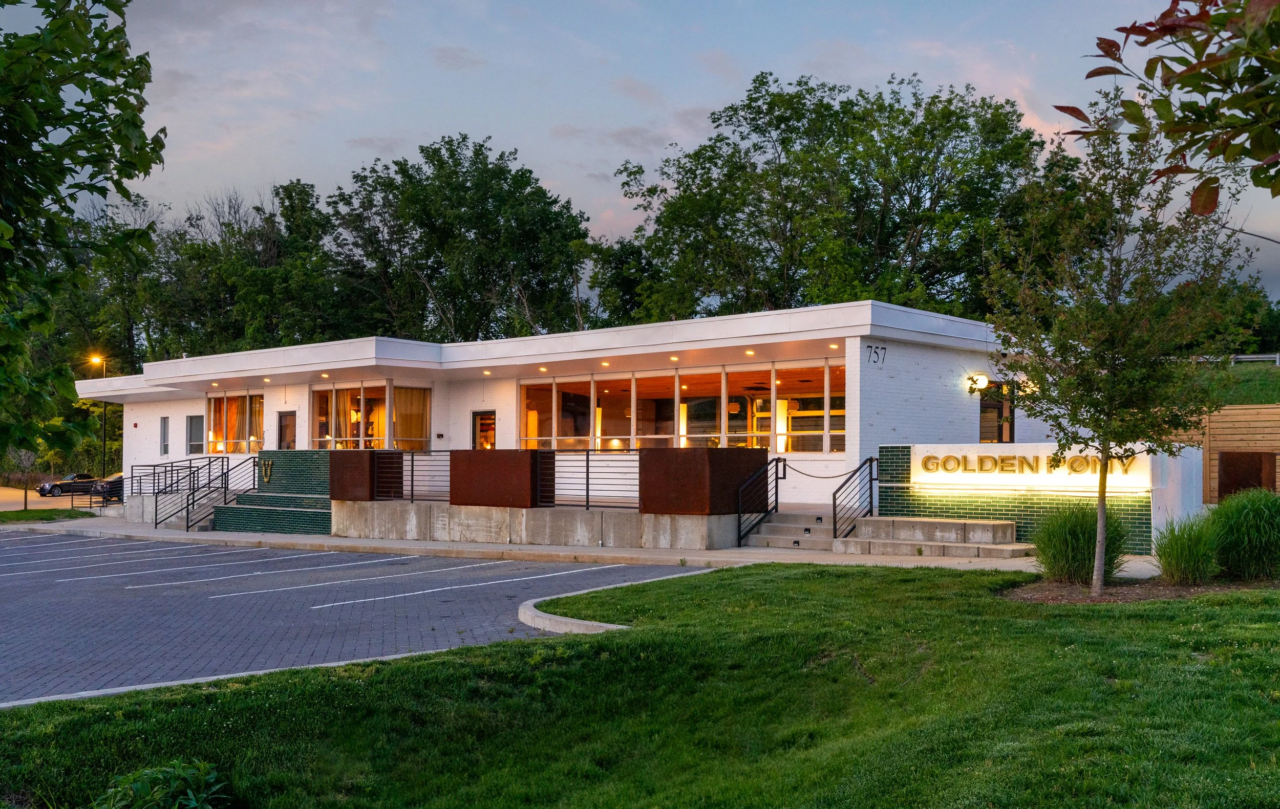 Twilight view of Golden Pony building with soft ambient lighting and lush greenery.