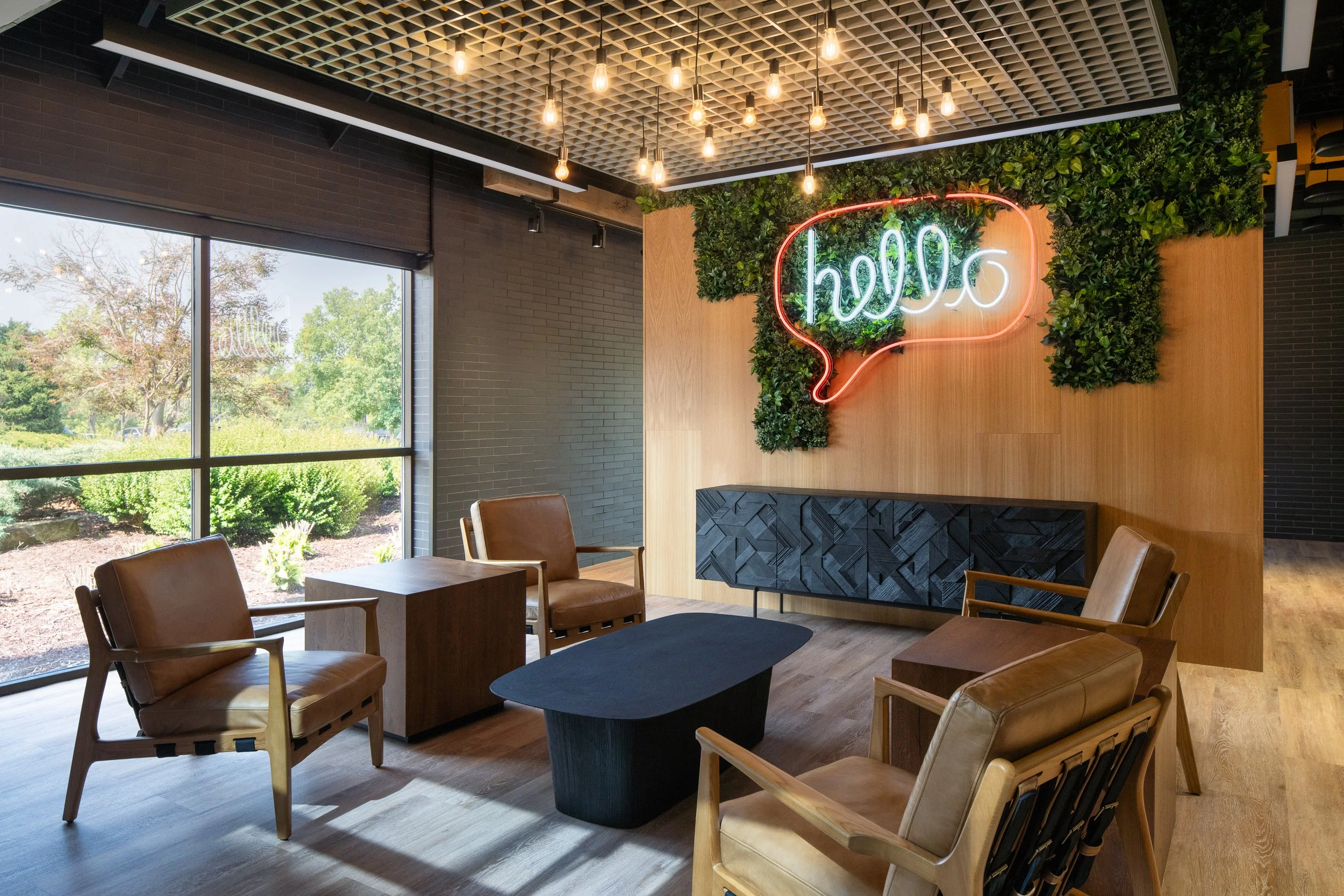 Stylish waiting area with leather chairs, greenery, and a neon "hello" sign.