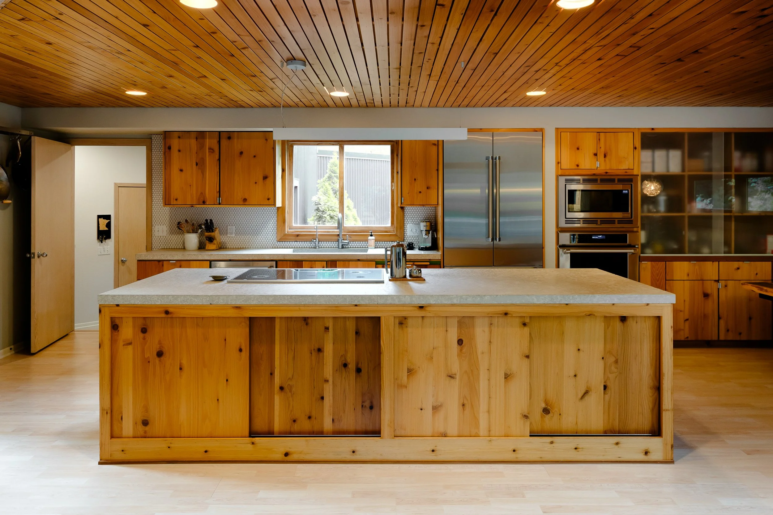 Spacious modern kitchen with a large wooden island and stainless steel appliances.