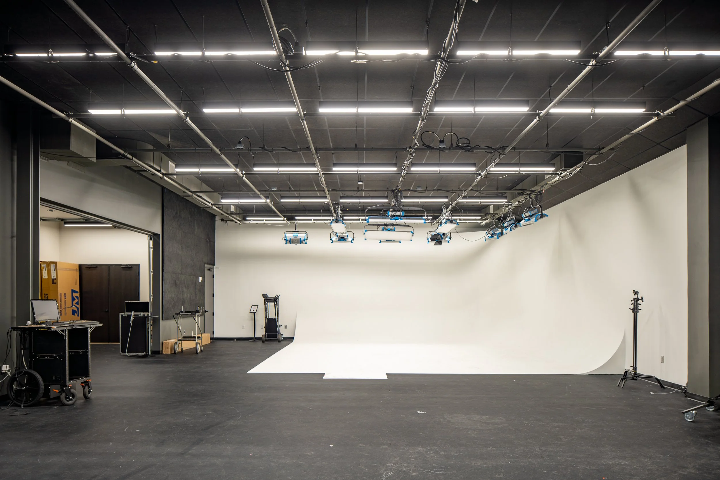 Large video production studio with a curved white backdrop and overhead lighting.