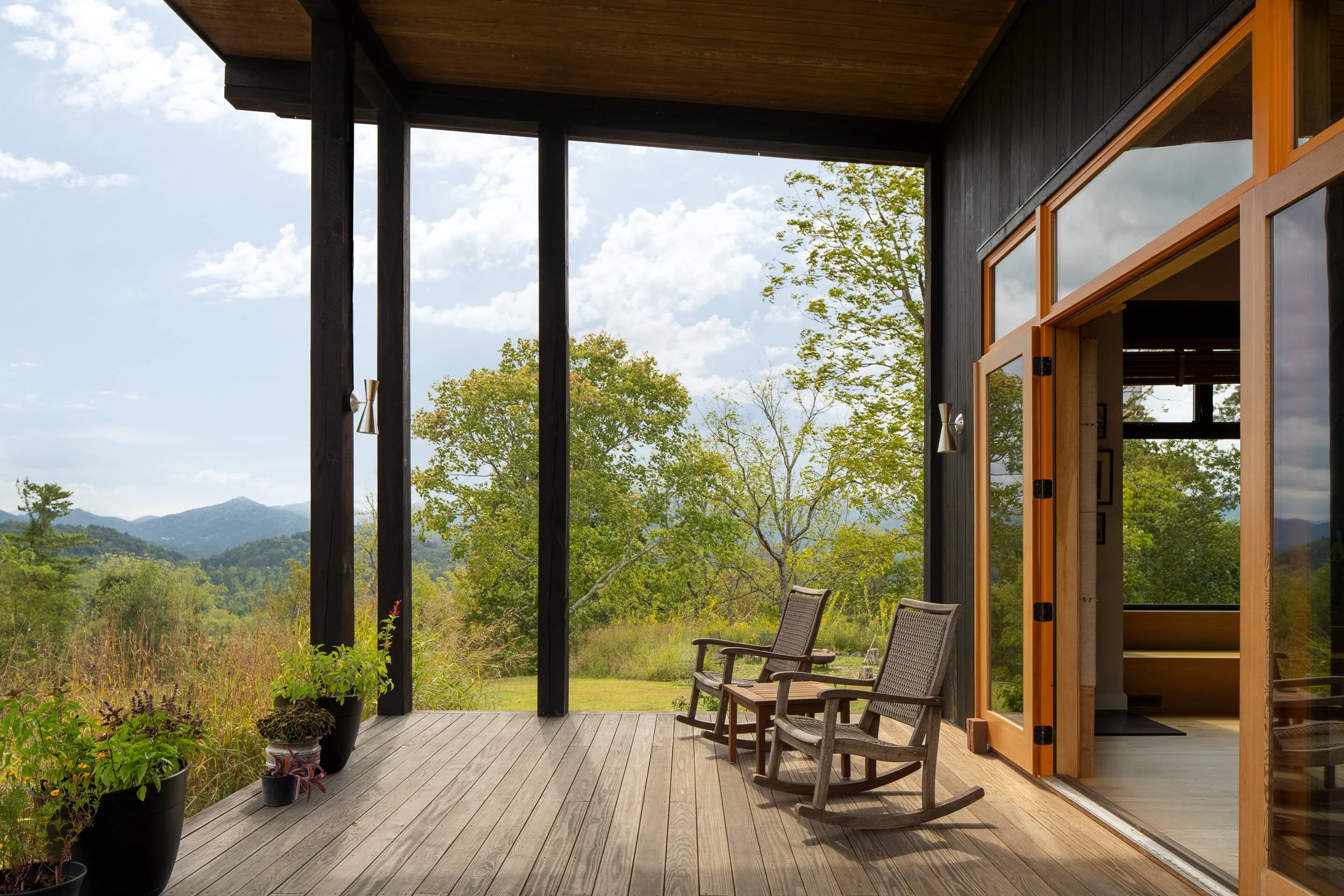 Covered porch with wooden rocking chairs overlooking mountain views.