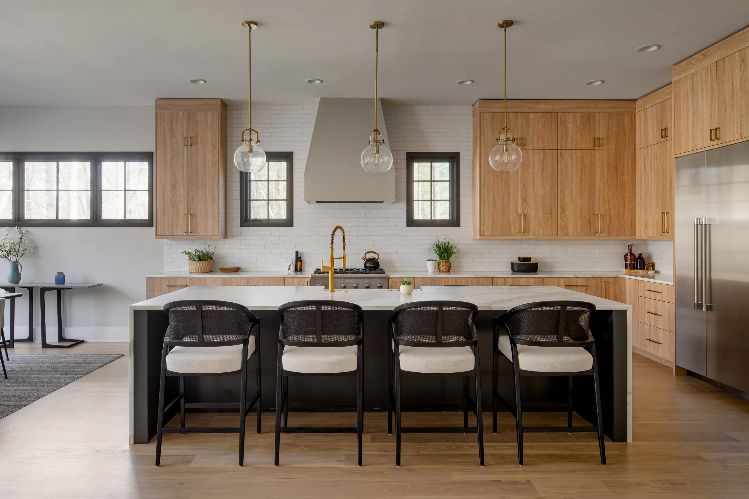 Contemporary kitchen with light wood cabinets, a central island, and modern lighting.