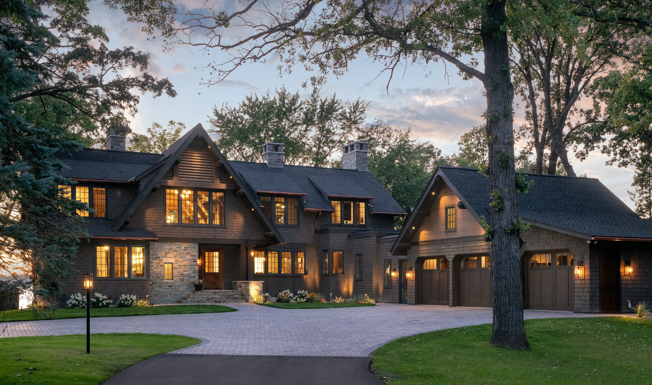 Craftsman home at dusk with lit windows and stone entry.