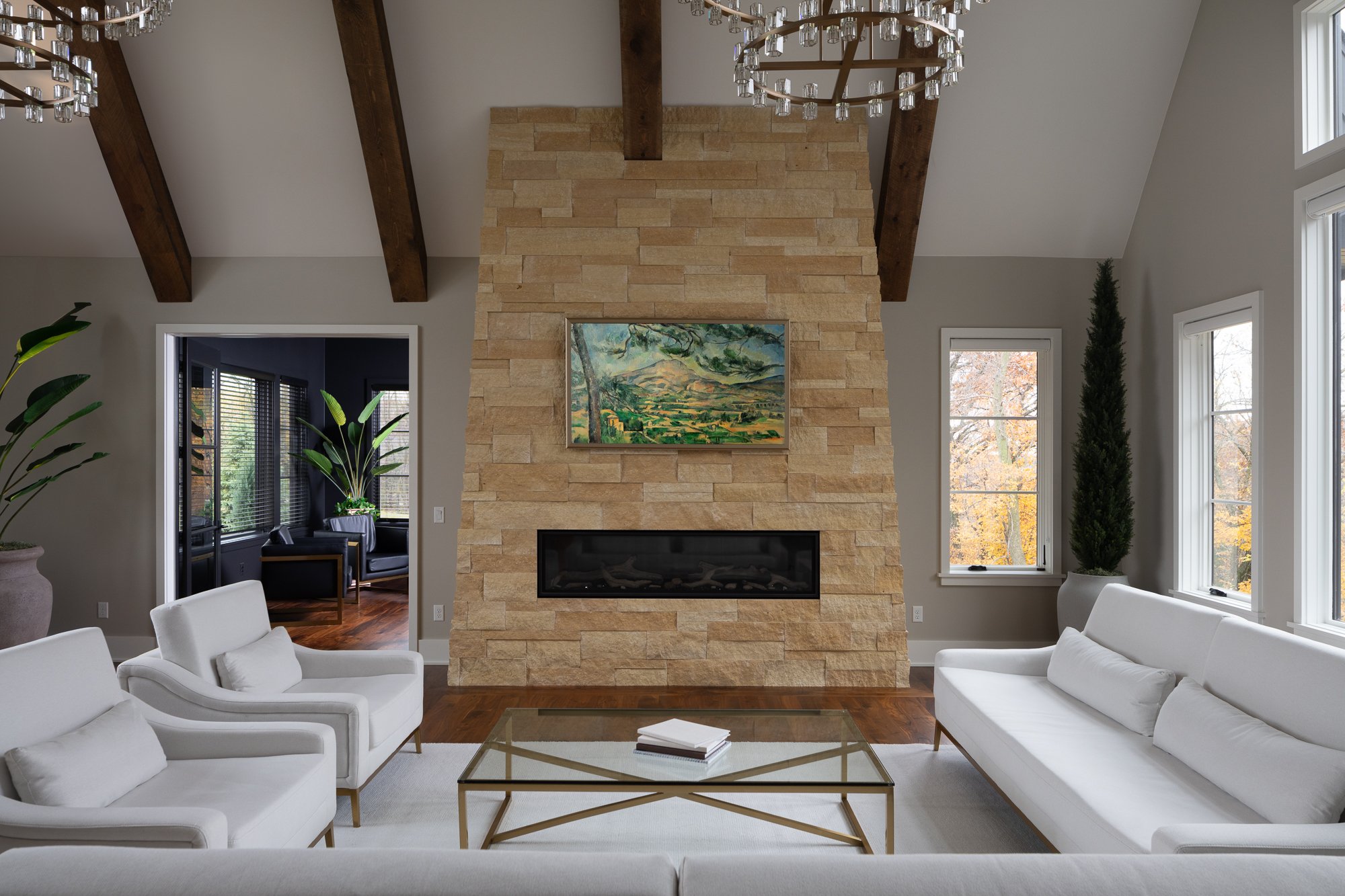 Modern living room with a floor-to-ceiling stone fireplace, neutral tones, and natural light.