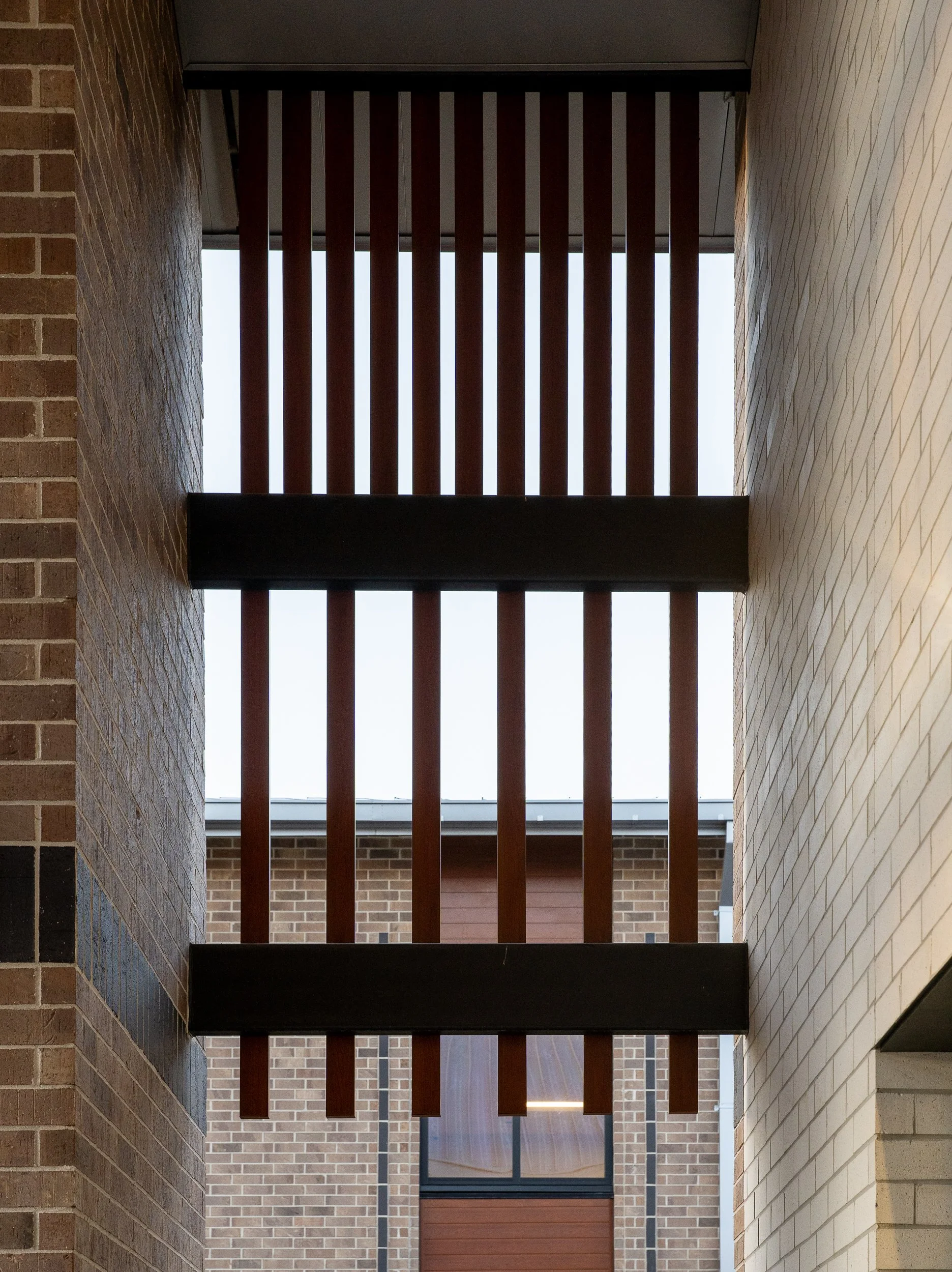 Vertical view of the entry canopy with brick columns, black steel structure, American flag, and surrounding landscape.
