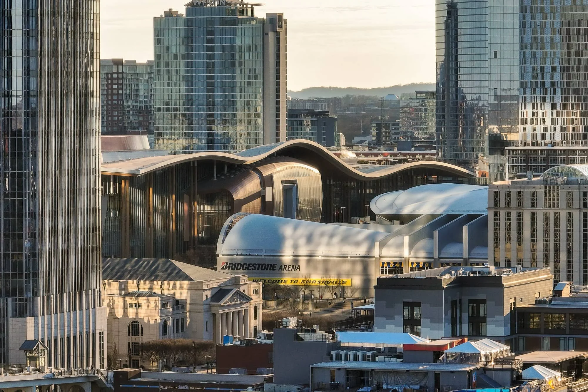 Aerial view of downtown Nashville skyline showing Bridgestone Arena, Music City Center, The Bridge Building, the Four Seasons Hotel under construction, and surrounding high-rises
