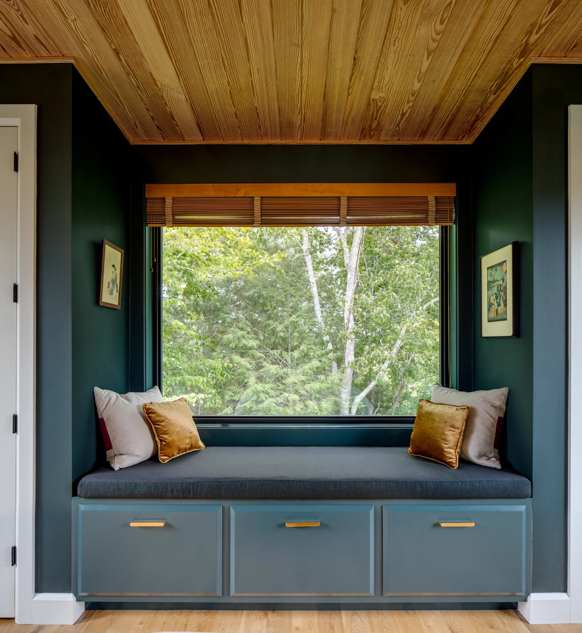 Built-in window seat with dark blue cabinetry and gold hardware.