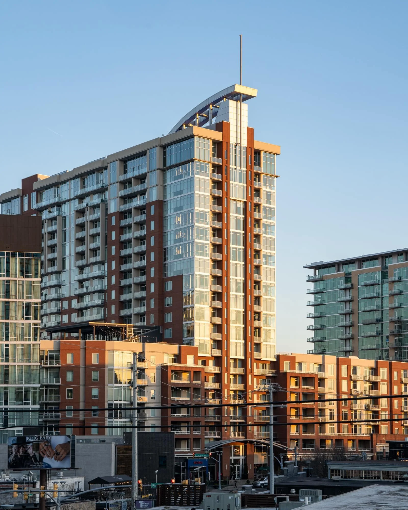 The Icon in The Gulch residential tower in Nashville with brick and glass facade, rooftop amenity level, and surrounding Gulch buildings in early morning light