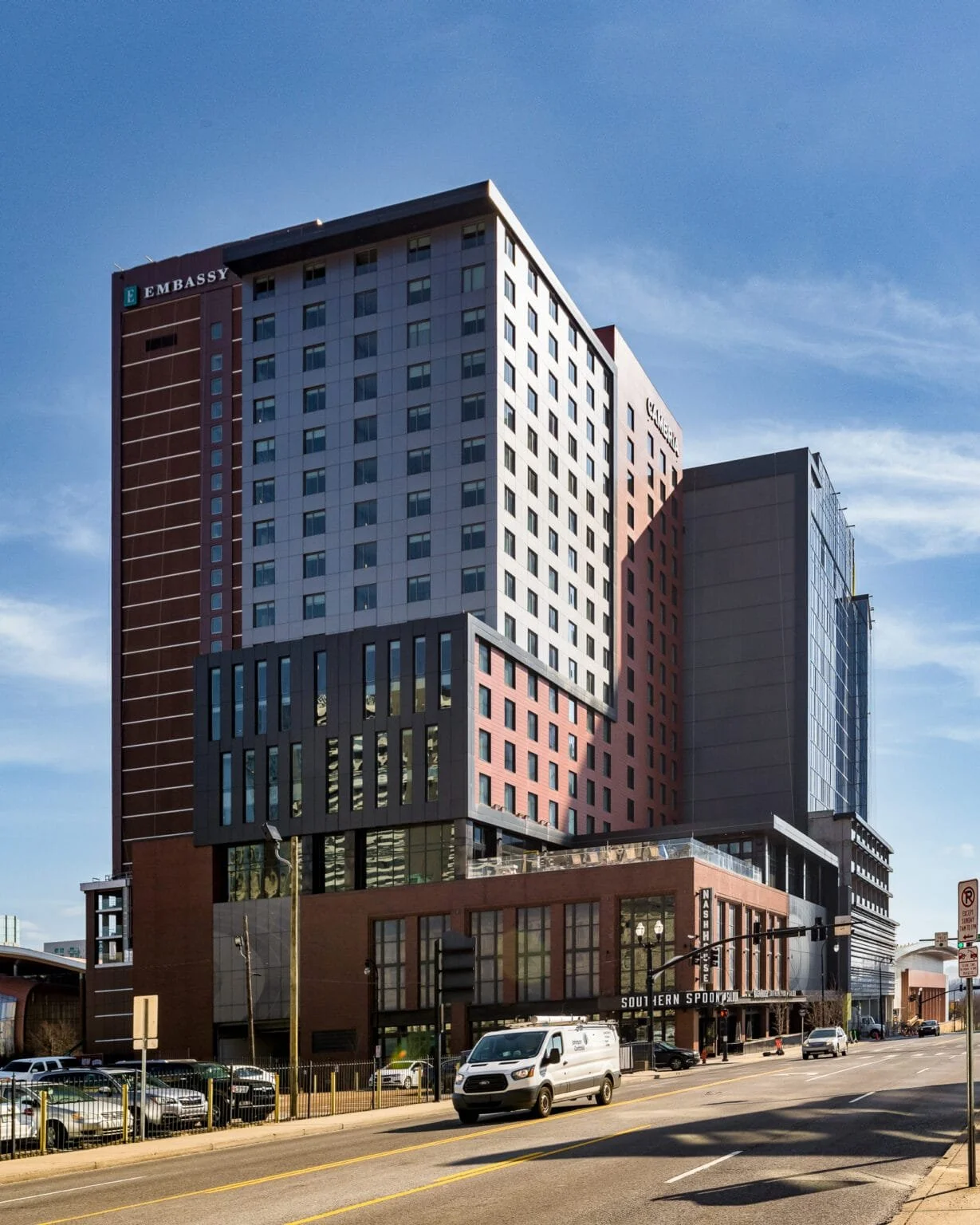 Cambria Hotel and surrounding downtown Nashville buildings photographed at midday with flat shadows and harsh top light across the facade