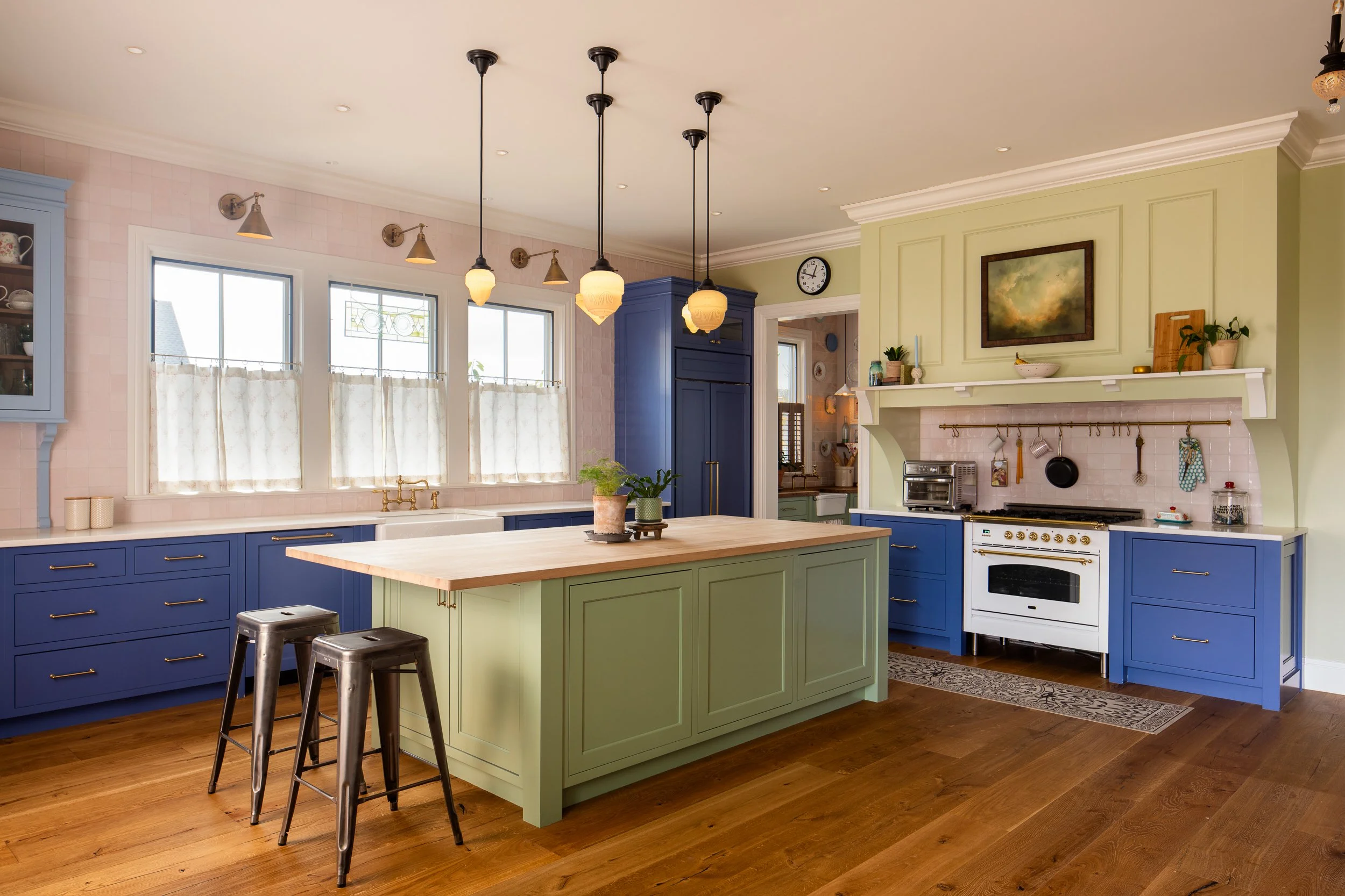 Kitchen range wall with blue cabinets, green surround, brass details, and wood flooring