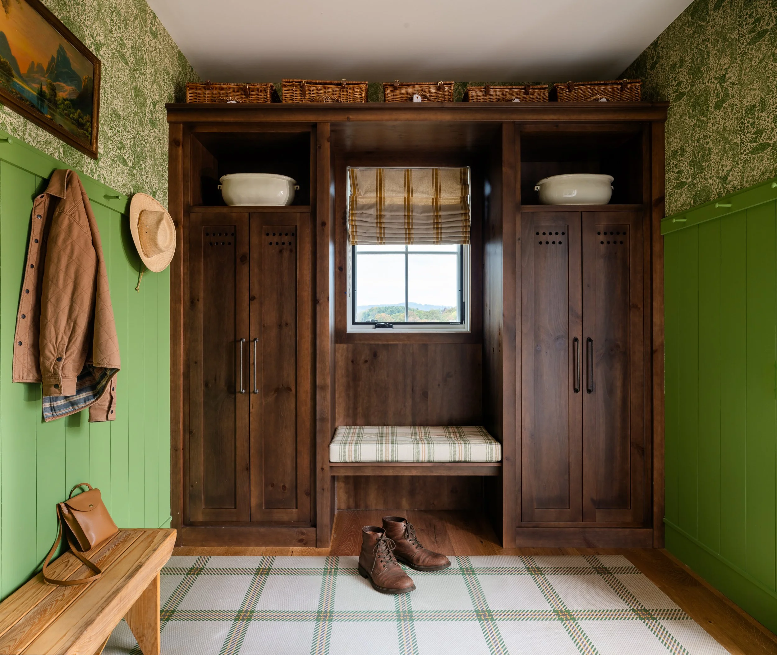 Mudroom with dark wood lockers, bench seating, green paneling, and woven baskets