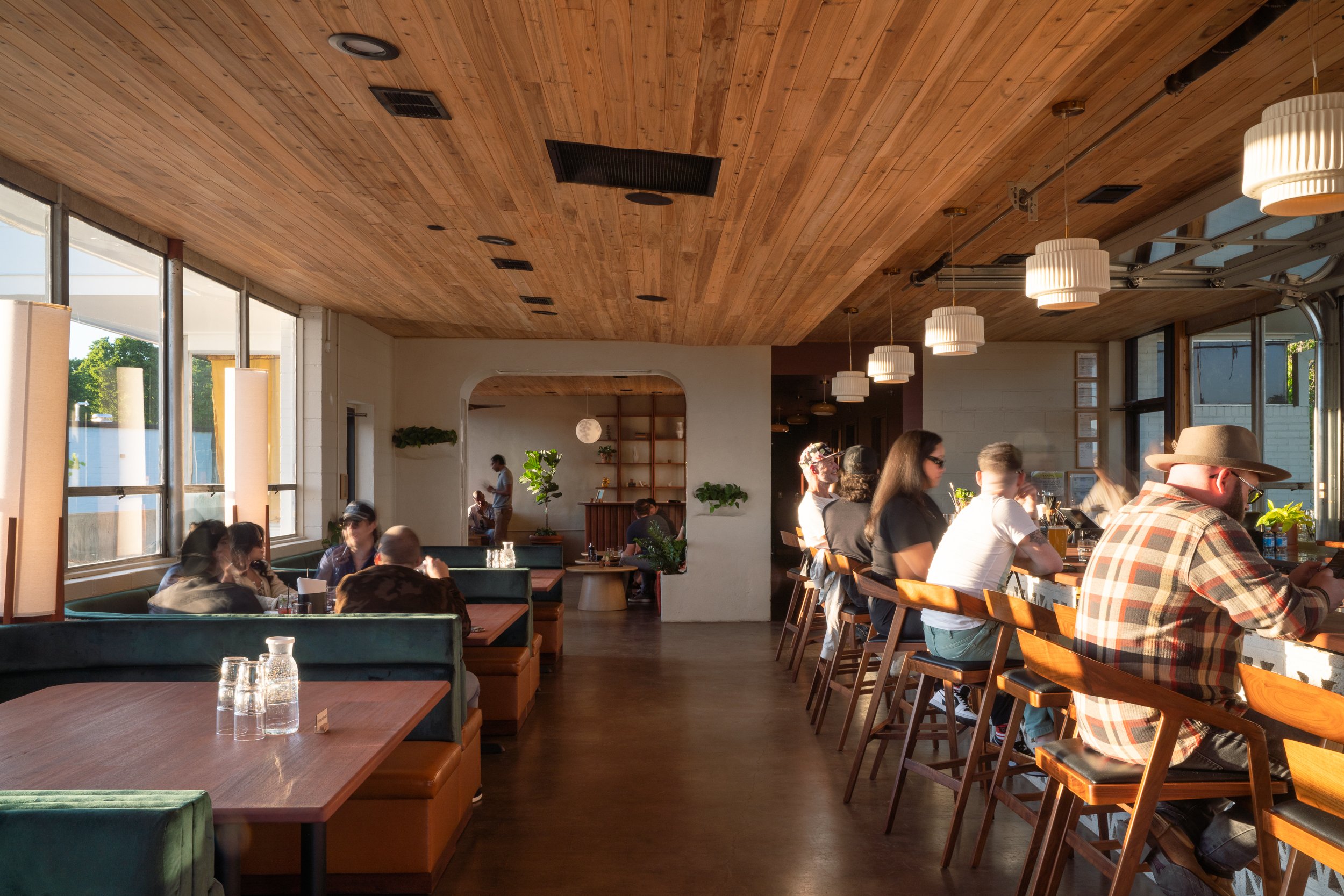 Guests seated at a cocktail bar with modern pendant lighting and wooden finishes.
