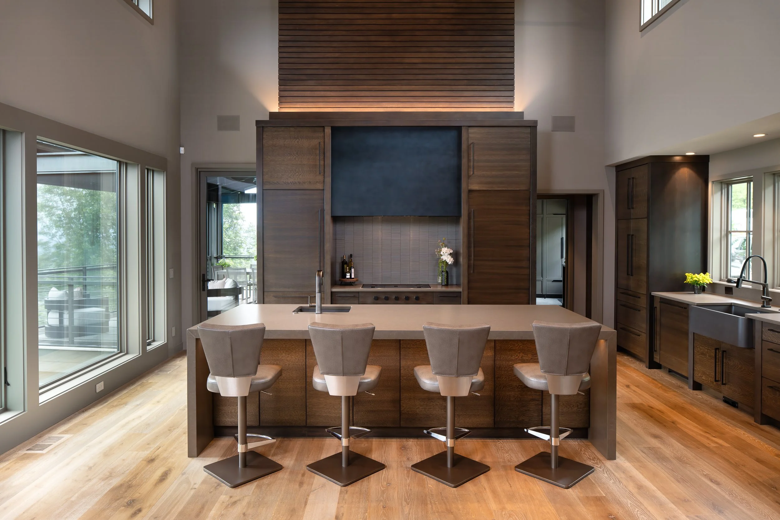 Modern kitchen with dark wood cabinetry, large island, and pendant lighting.