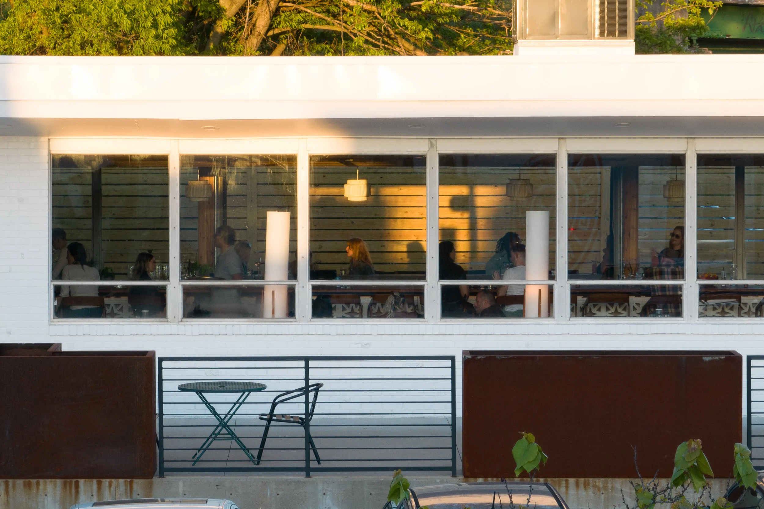 Street-level view of bar interior through large glass windows.