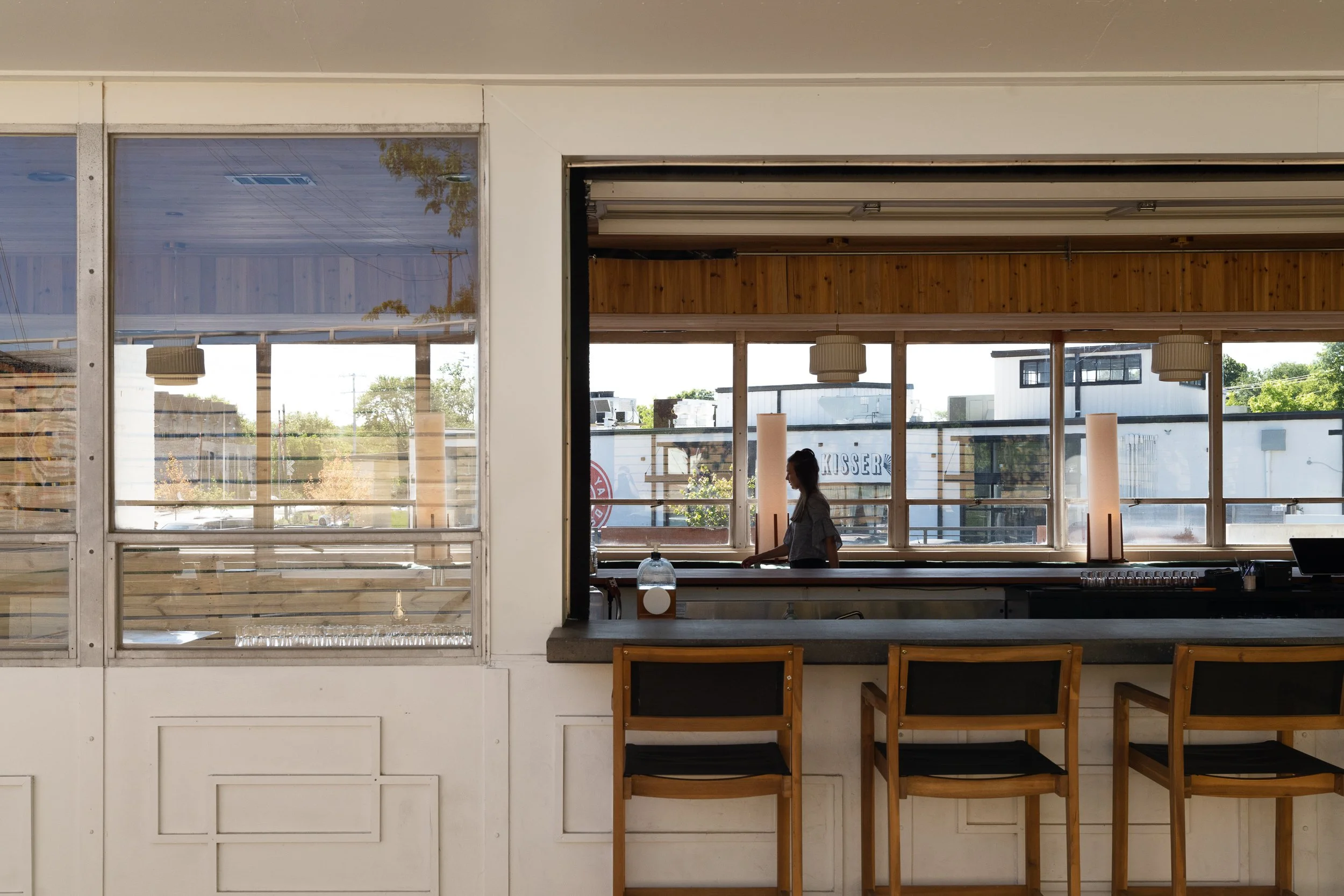 View into the bar interior through an open garage-style window.