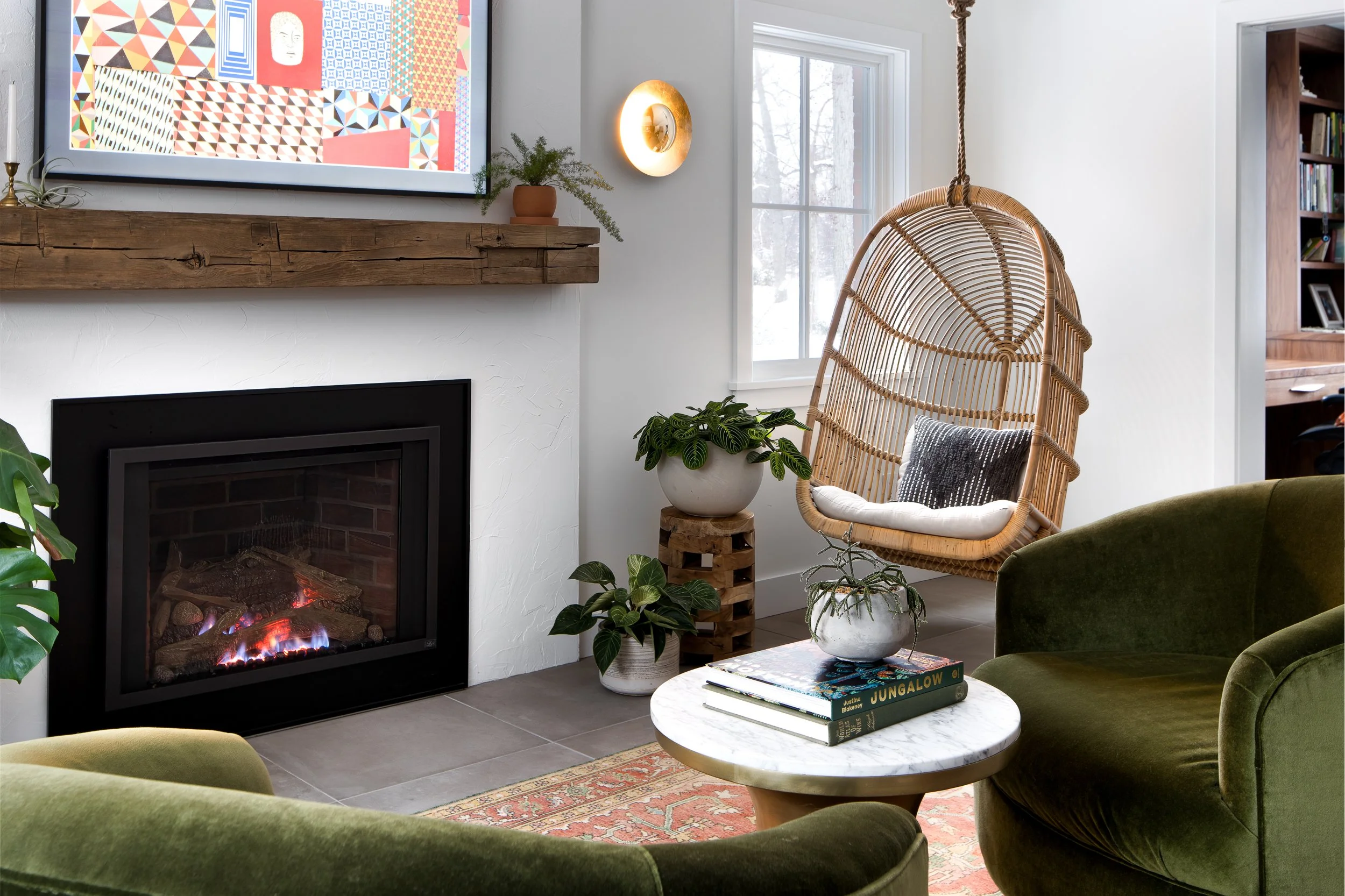 A modern fireplace mantel with a rattan hanging chair in a cozy living room.