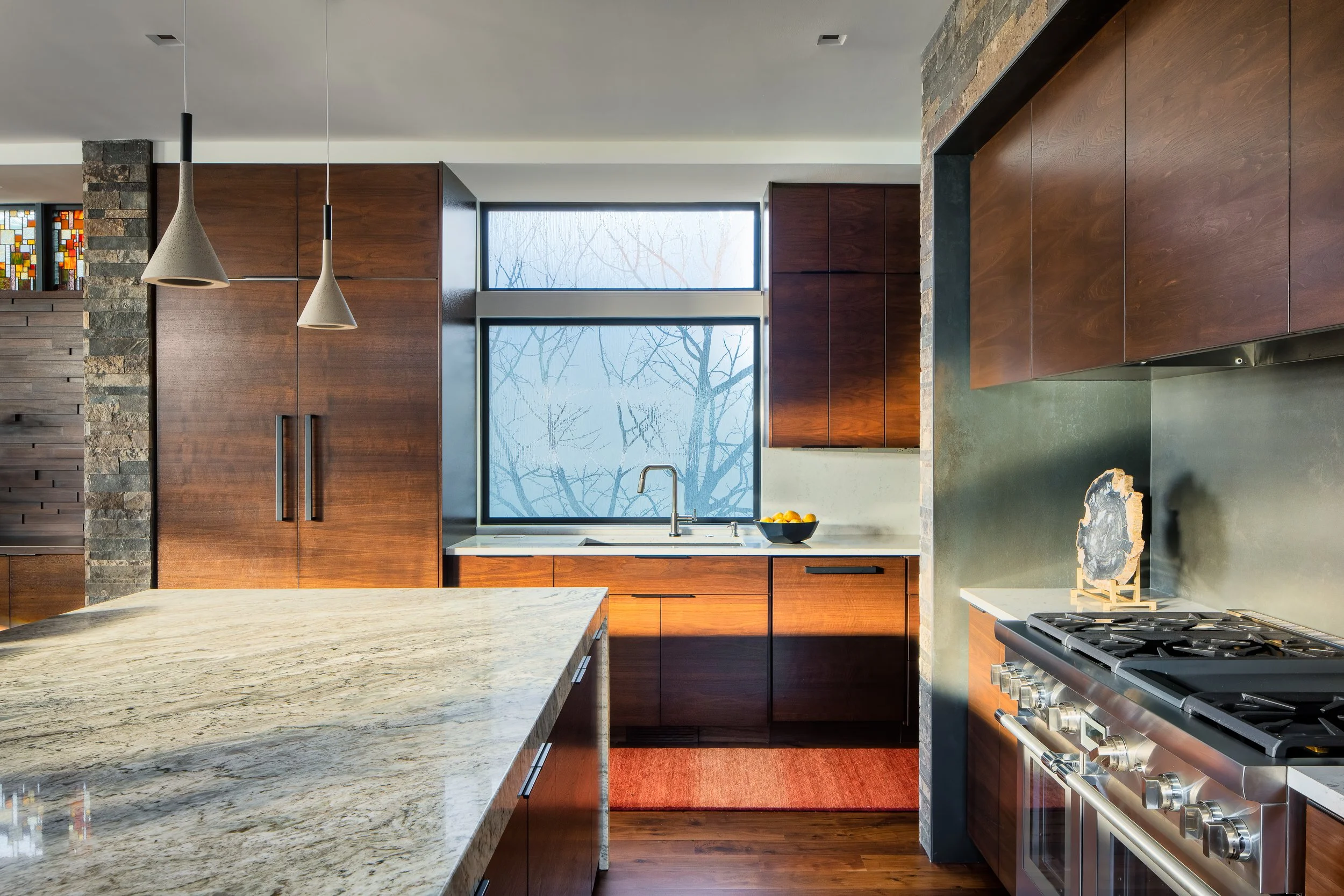 Modern kitchen with wood cabinetry, pendant lights, and frosted glass windows.