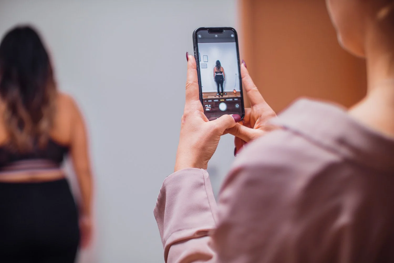 Person, die ein Foto von einer anderen Person mit einem Smartphone macht.