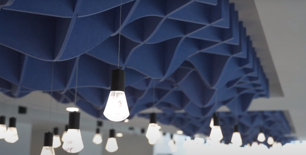 Ceiling with hanging light bulbs and a blue acoustic panels.