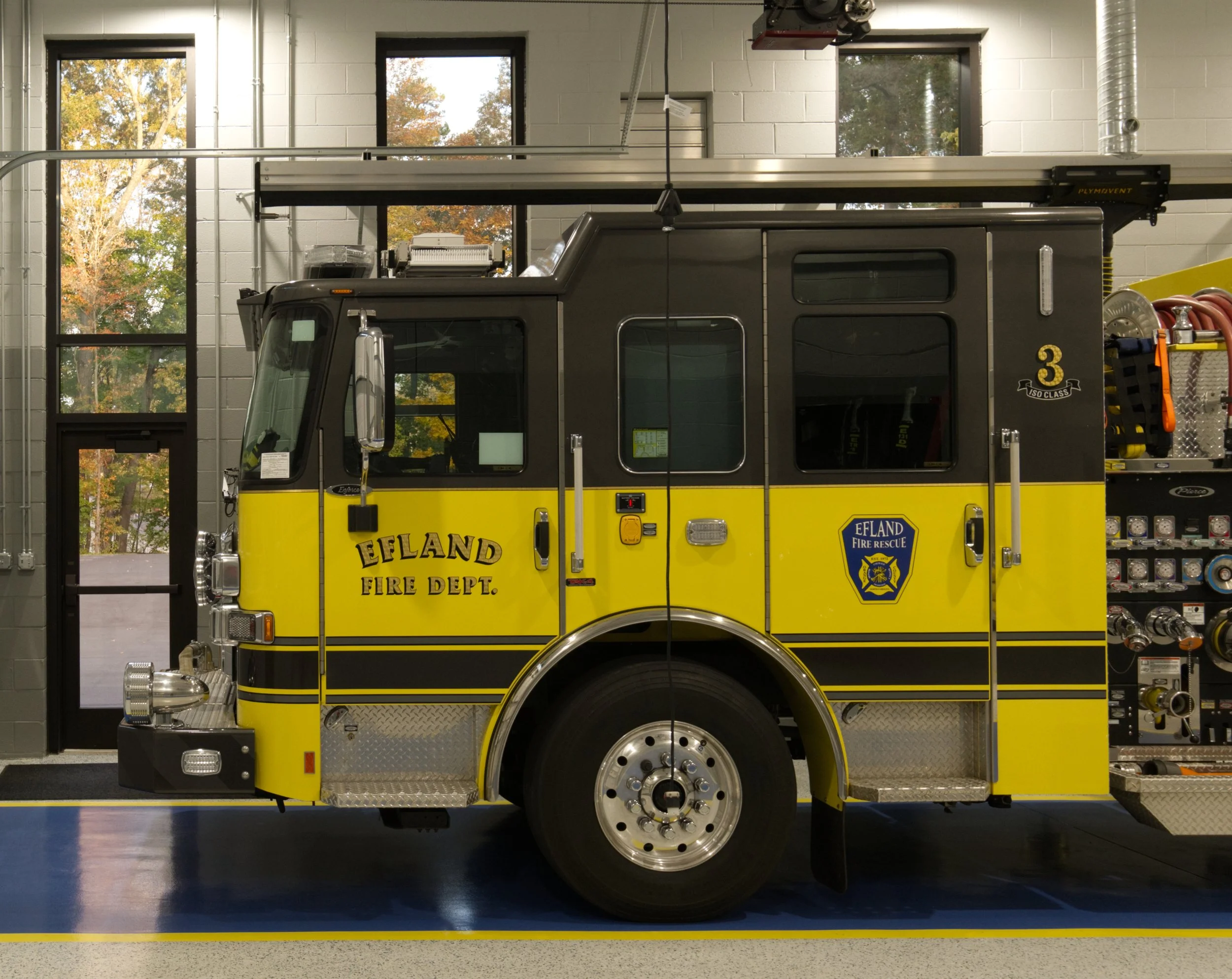 A yellow and black fire truck inside a fire station. The truck has 'Efland Fire Dept.' written on it, with a blue fire rescue badge on the side.