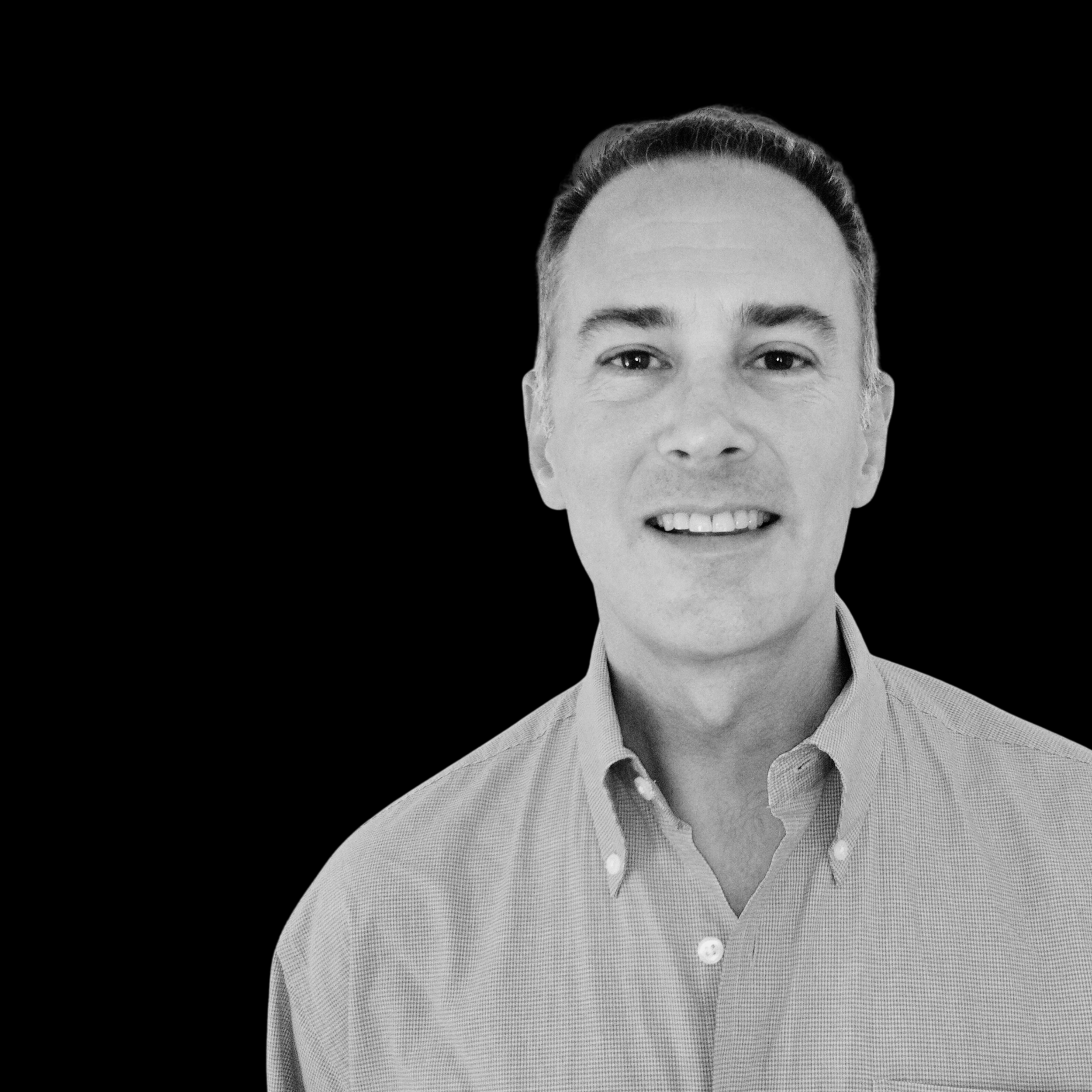 Black and white portrait of a smiling man wearing a collared shirt against a black background.