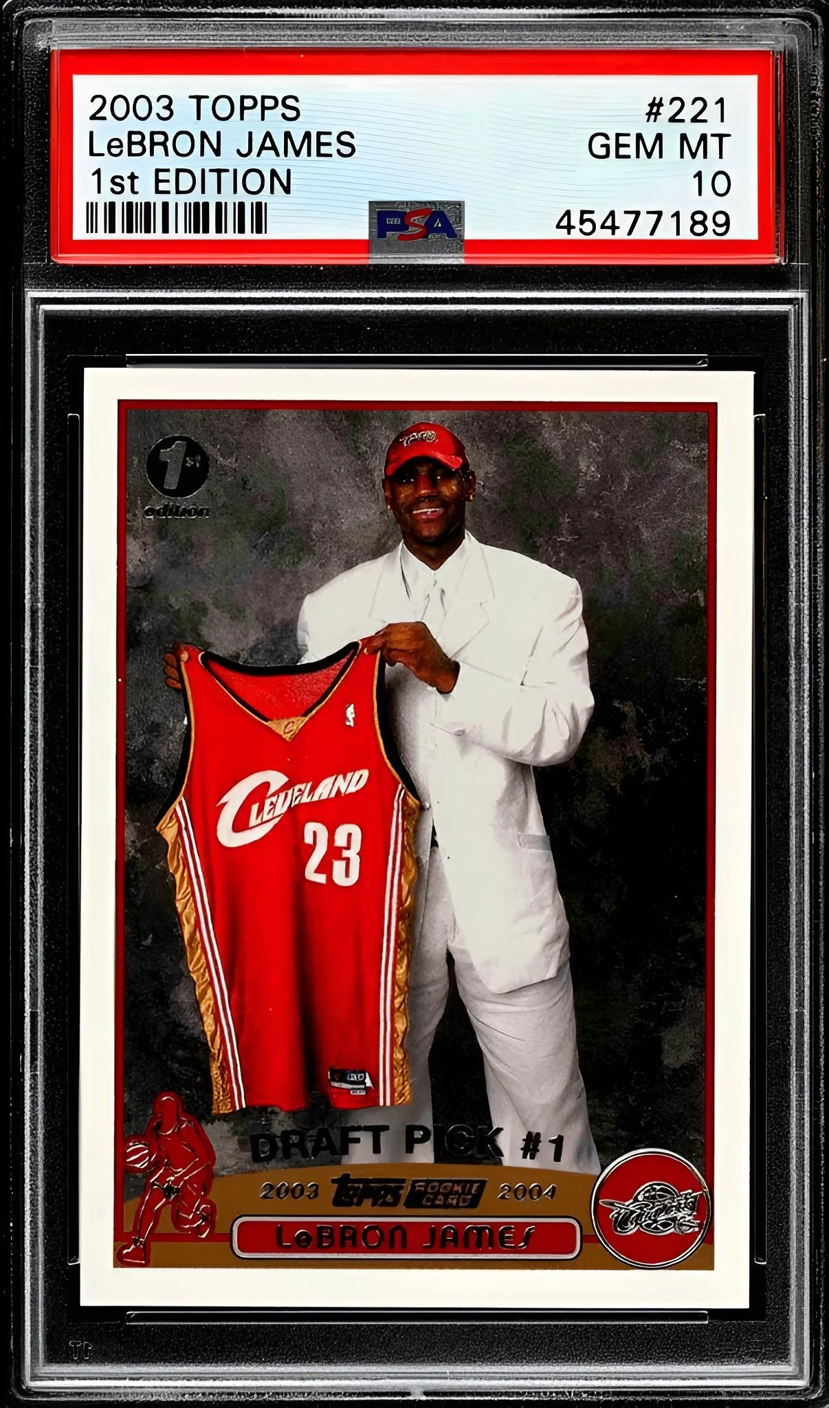 A trading card featuring LeBron James in a white suit, holding a Cleveland Cavaliers basketball jersey with the number 23. The card is labeled '2003 Topps Draft Pick #1' and shows he was selected in the first round of the 2003 NBA Draft.