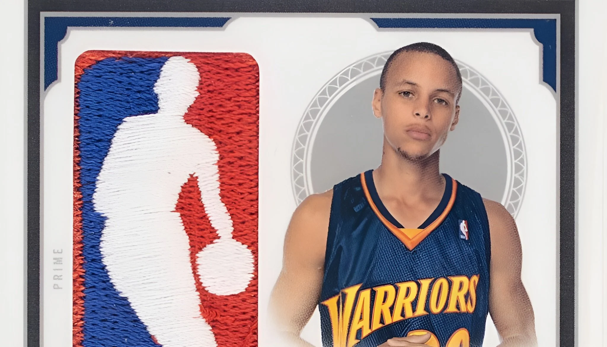 A basketball trading card featuring a player from the Golden State Warriors, dressed in a dark blue Warriors jersey with gold and orange accents, standing with a serious expression. To the left, an embroidered NBA logo with a white silhouette of a ba