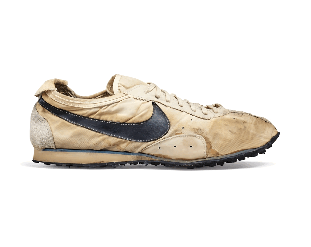 A worn, vintage Nike running shoe with a beige and black color scheme, showing significant signs of dirt and damage.