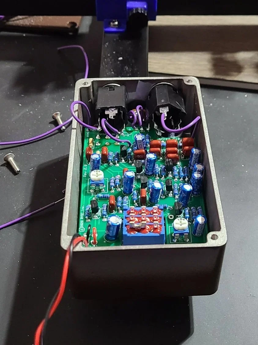 Close-up of precision soldering on a printed circuit board for a custom analog guitar pedal build.