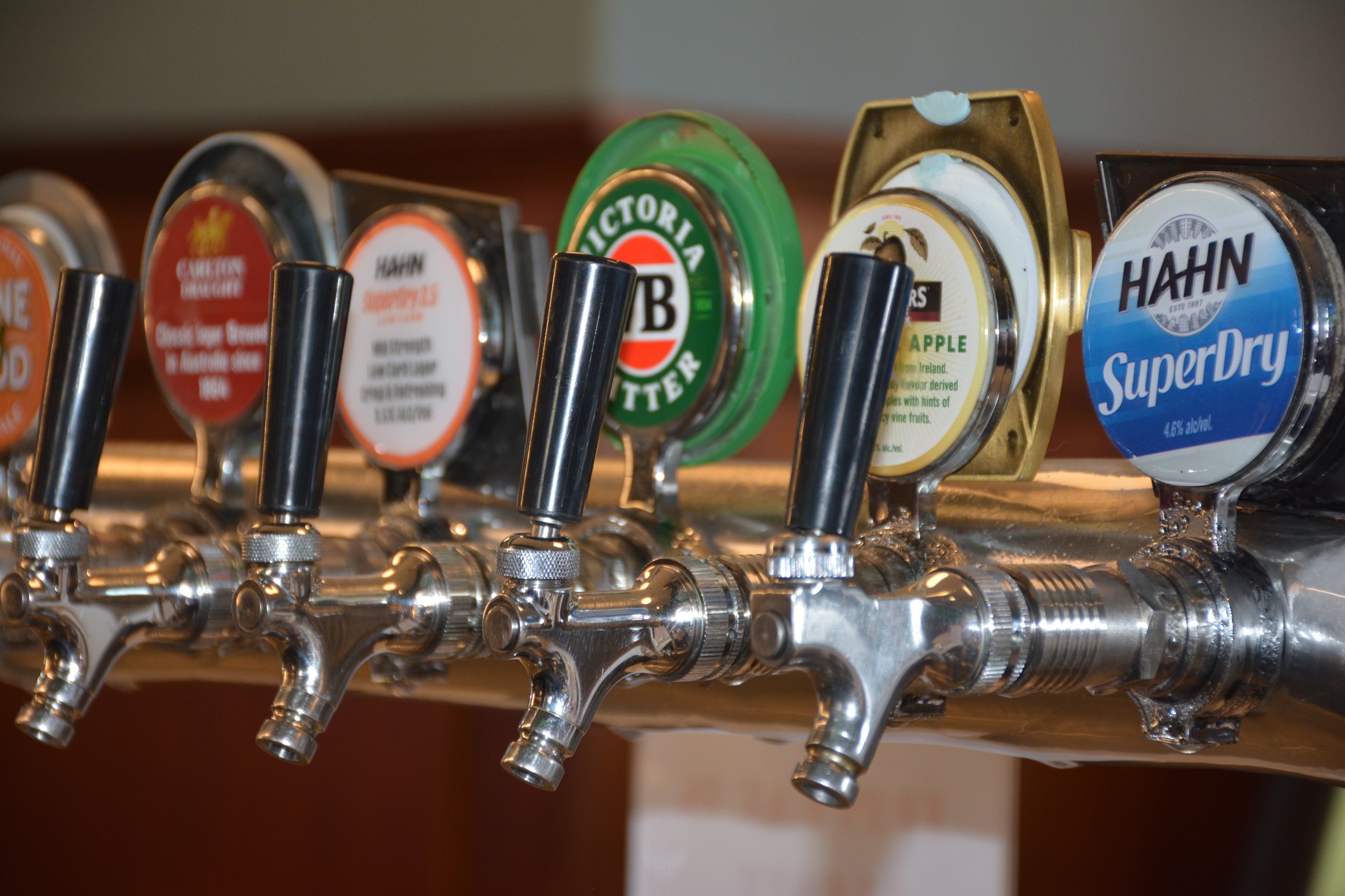 Close-up of beer tap handles featuring various beer brands mounted on a metallic draft system.