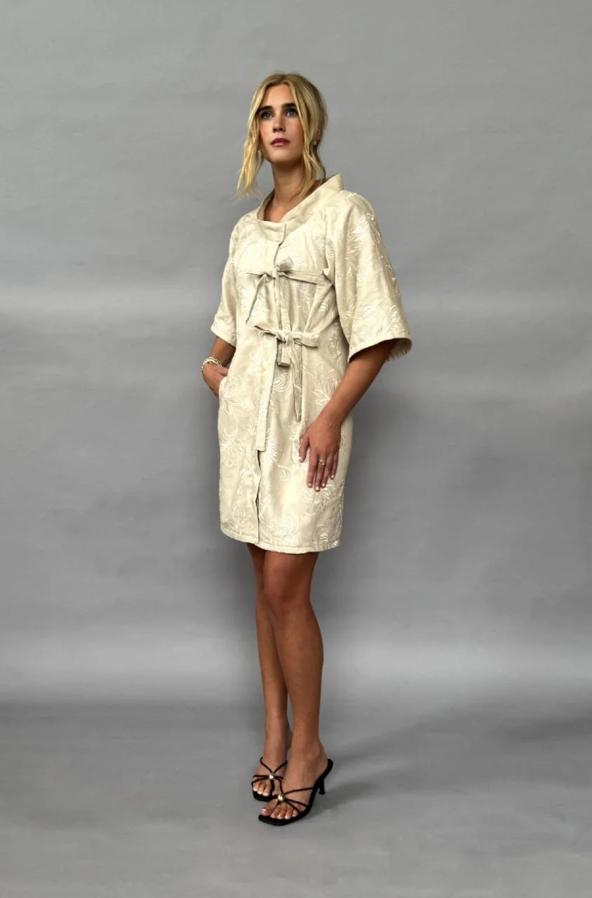 Model wearing Gracie Monsees's ivory zero-waste kimono-style dress against a gray studio backdrop.