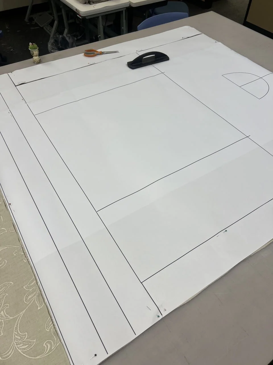 Full-scale zero-waste garment pattern pieces drawn on paper atop a worktable.