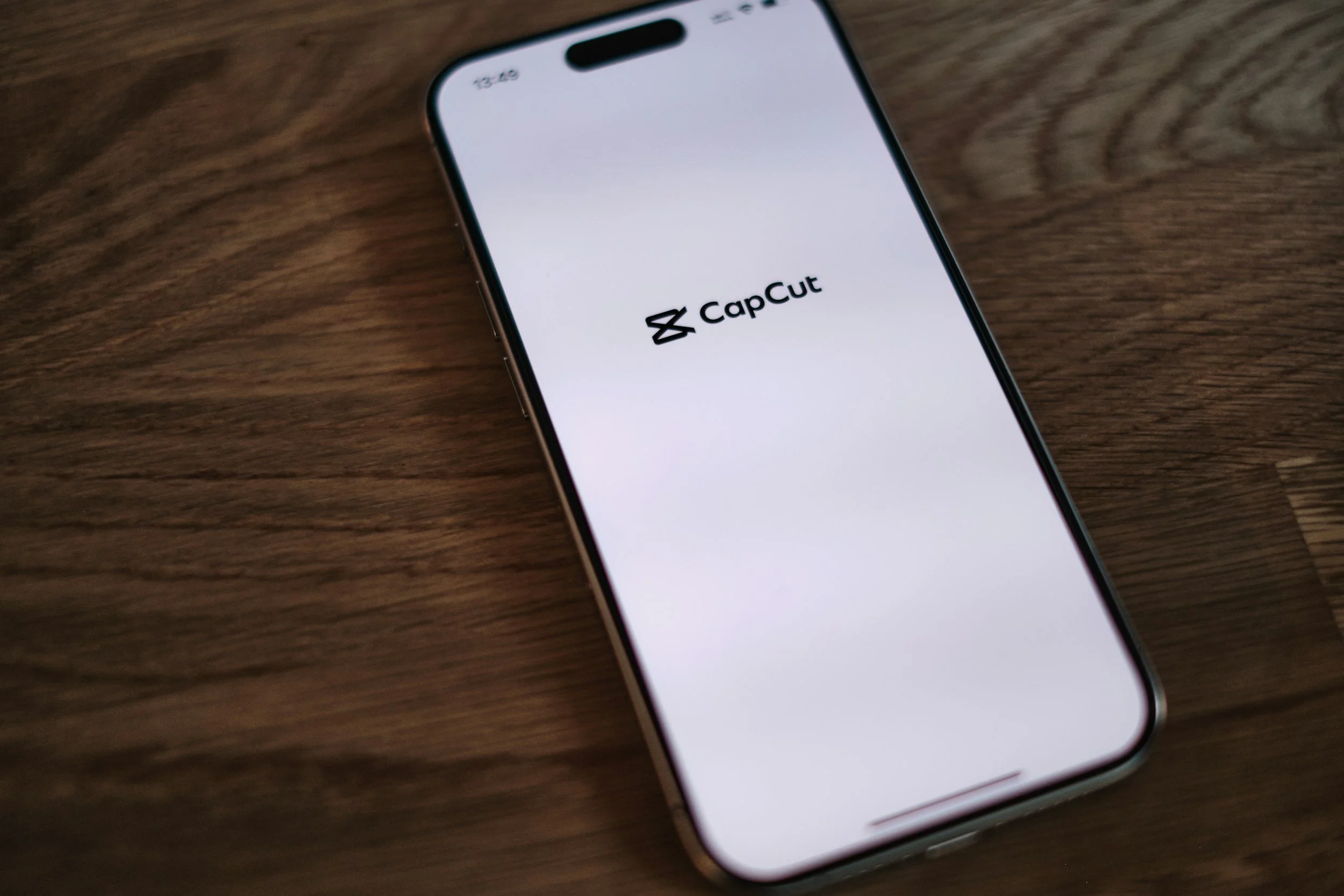 Smartphone displaying the CapCut app logo on a wooden surface.