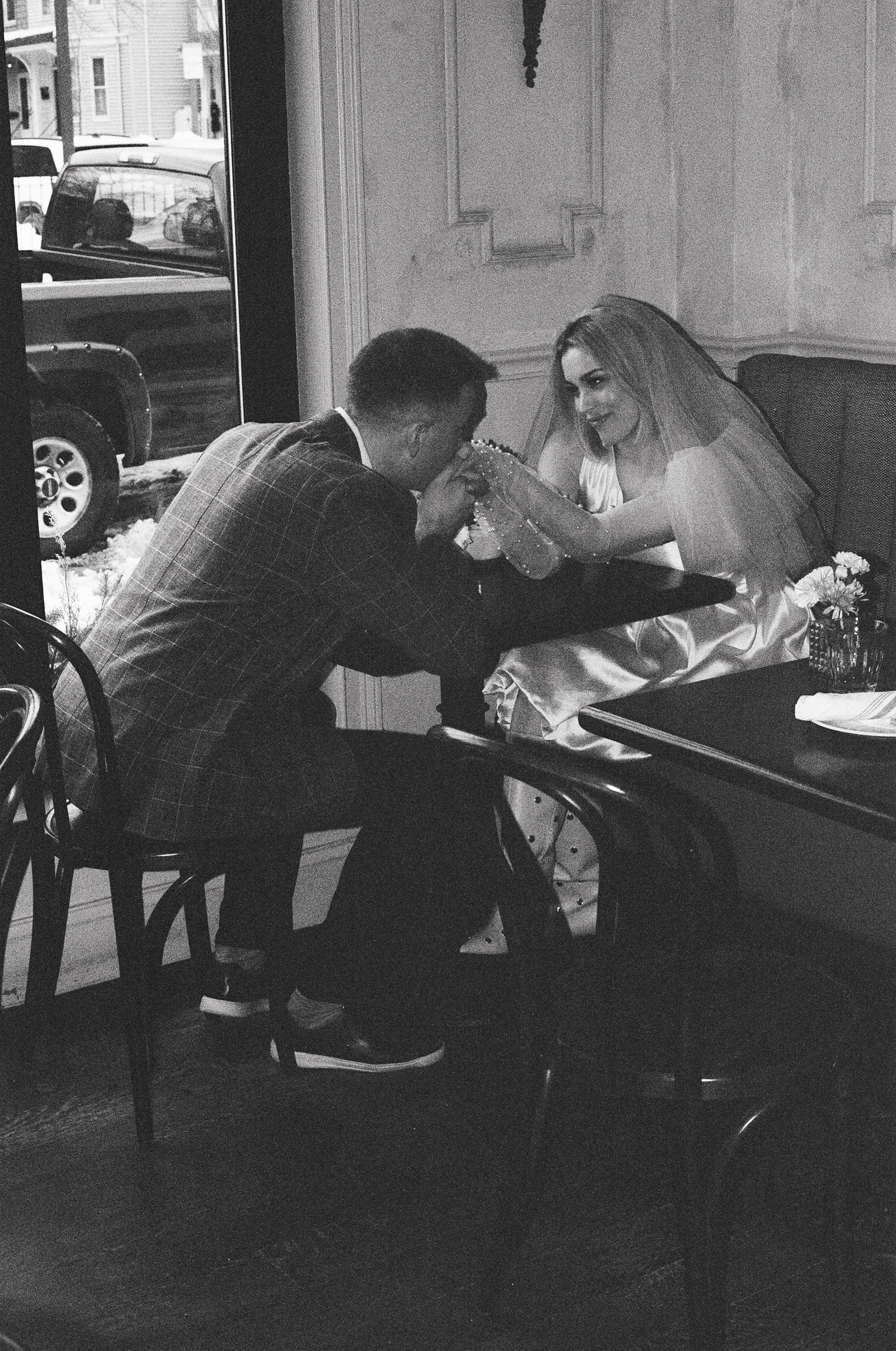 man kisses woman's hands over coffee on film