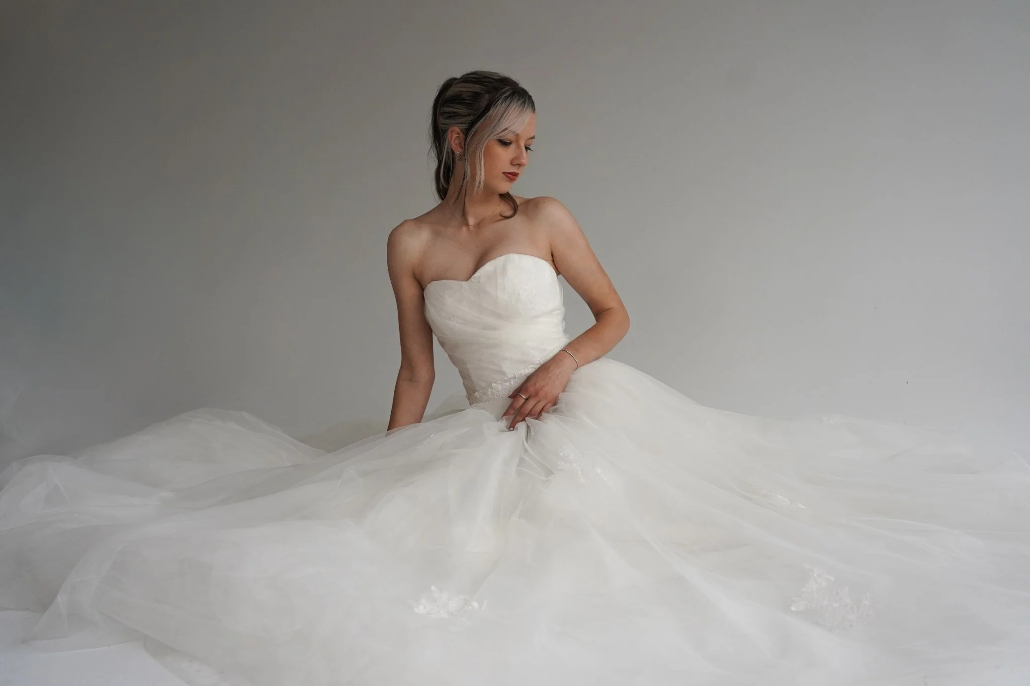 Woman in white silk pajamas smiling while looking at phone