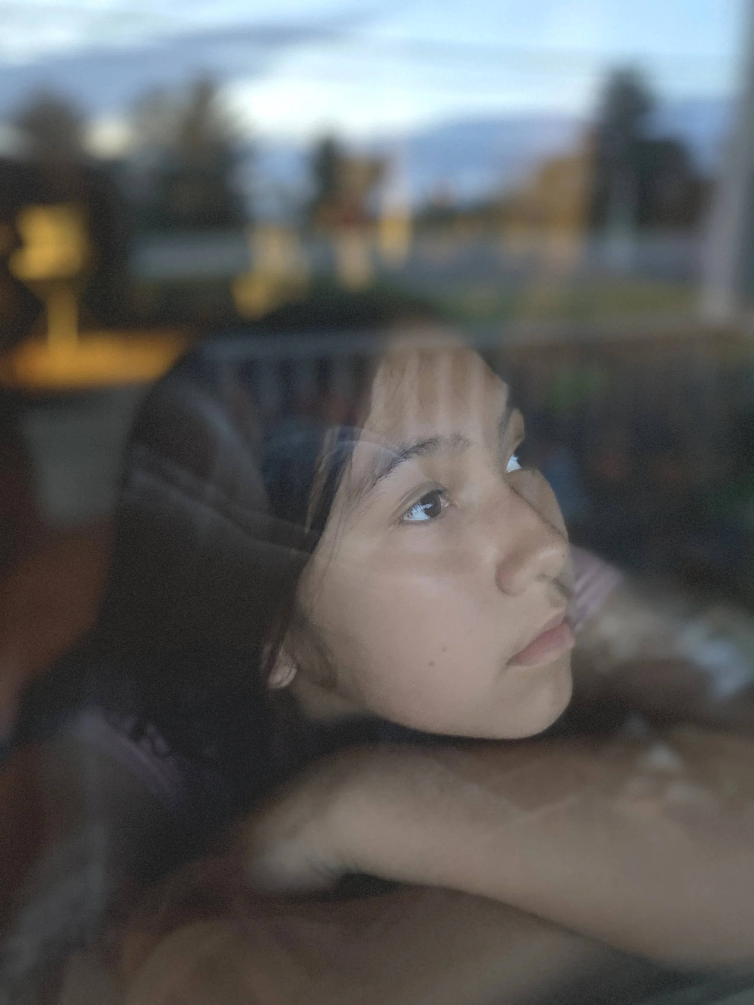 A young woman with shoulder-length brown hair and light skin taking a selfie outdoors on a sunny day.