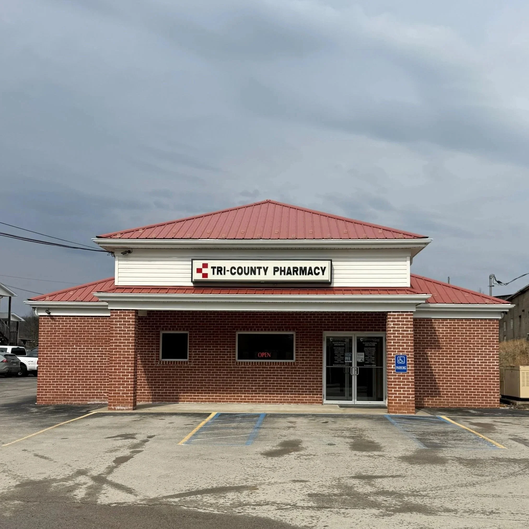 Front view of a community care center building with a sign that says 'Community Care of West Virginia' and 'Walk-ins Welcome' in front of a parking area.