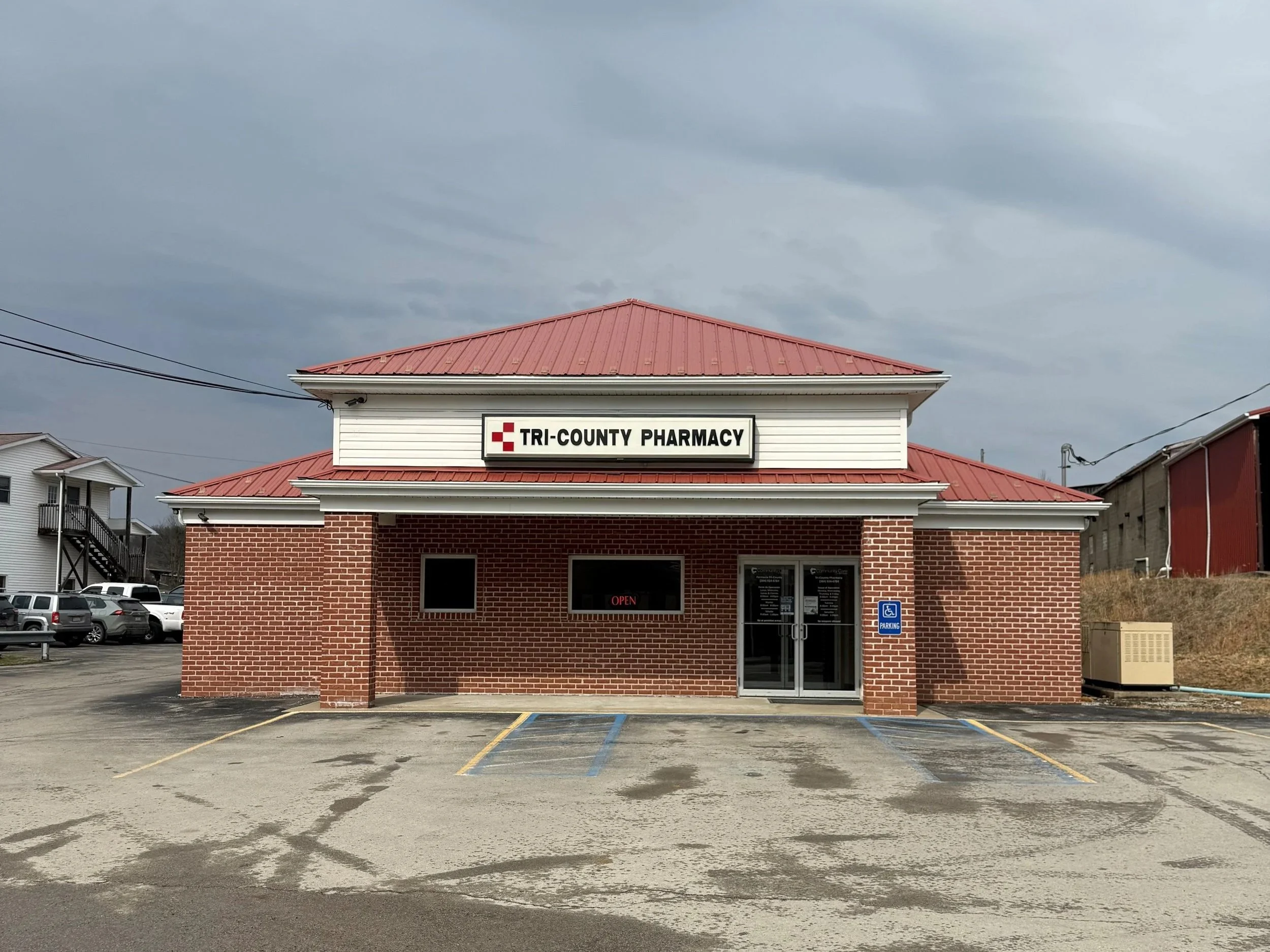 Front view of a county pharmacy building with a brick exterior and a red roof, featuring a sign that reads 'Kern County Pharmacy'.