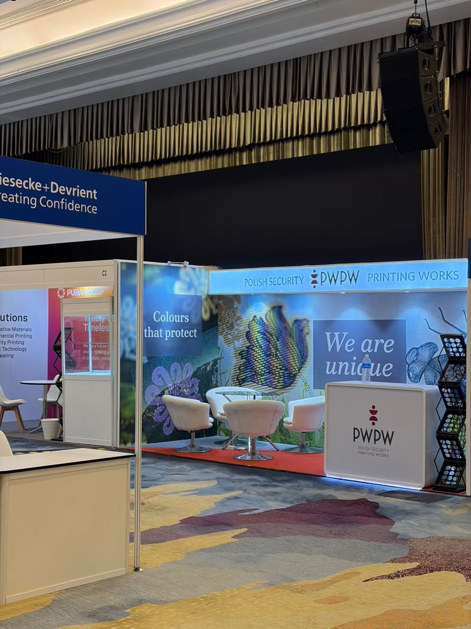 Trade show booth with seating area, banners, and signage for Polish Security Printing Works (PDW).