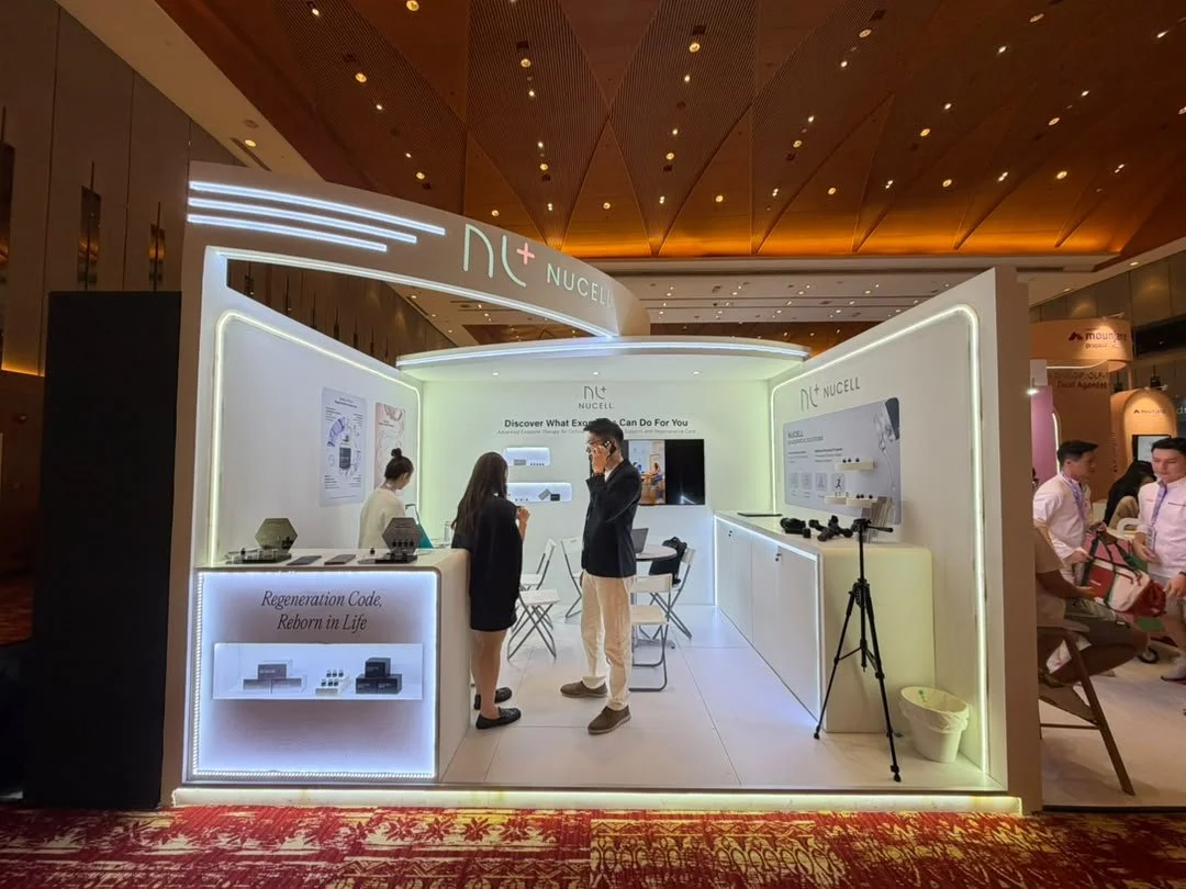 An exhibition booth for Nucell at a convention or trade show, featuring display boards, products, and people interacting inside.