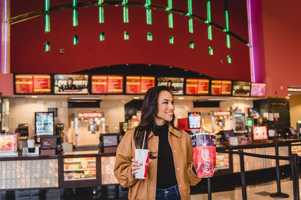 Woman holding drink and popcorn in front of Starlight Triangle Cinema concession