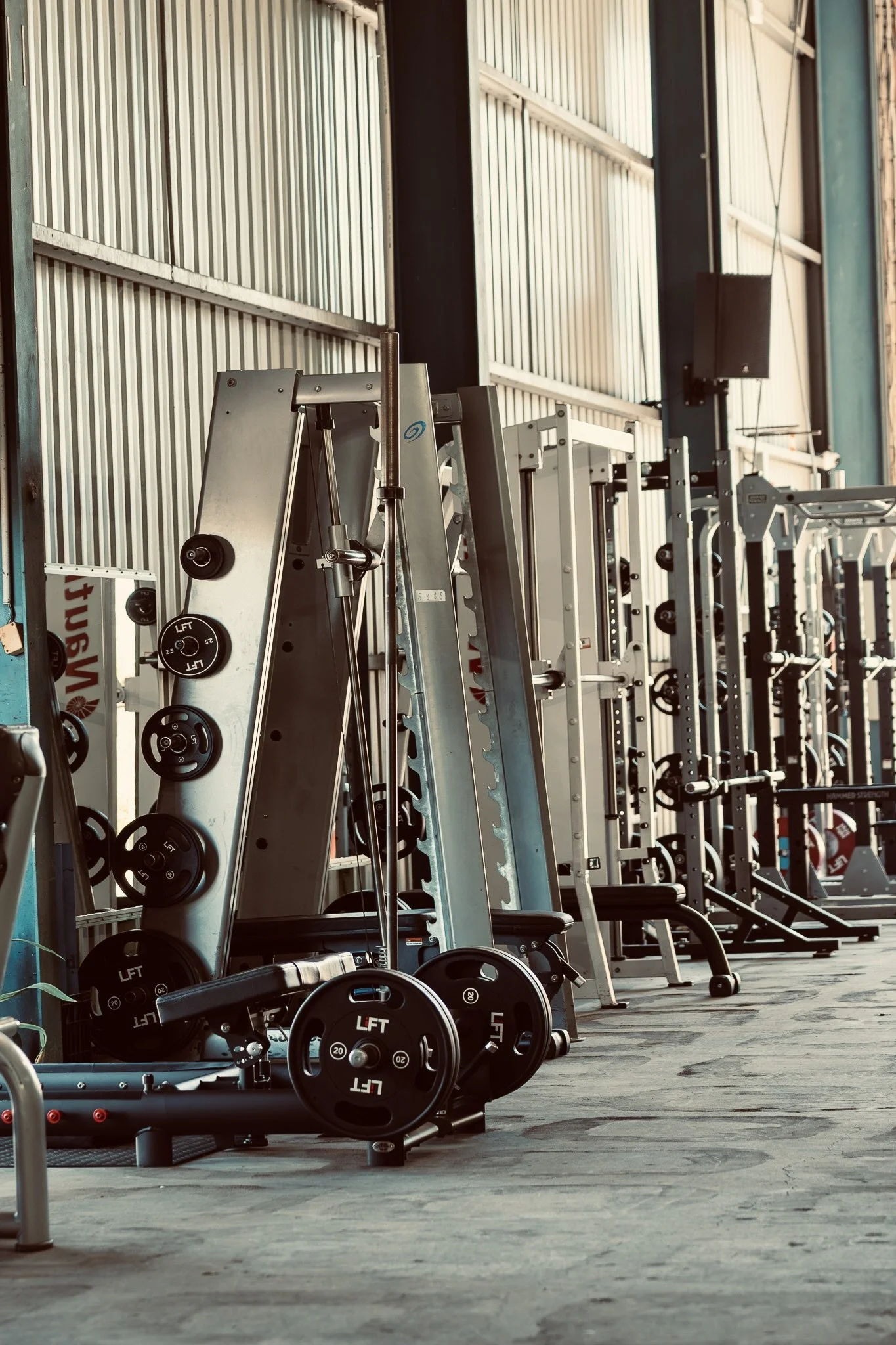 A row of gym equipment and weights in an industrial-style fitness center.