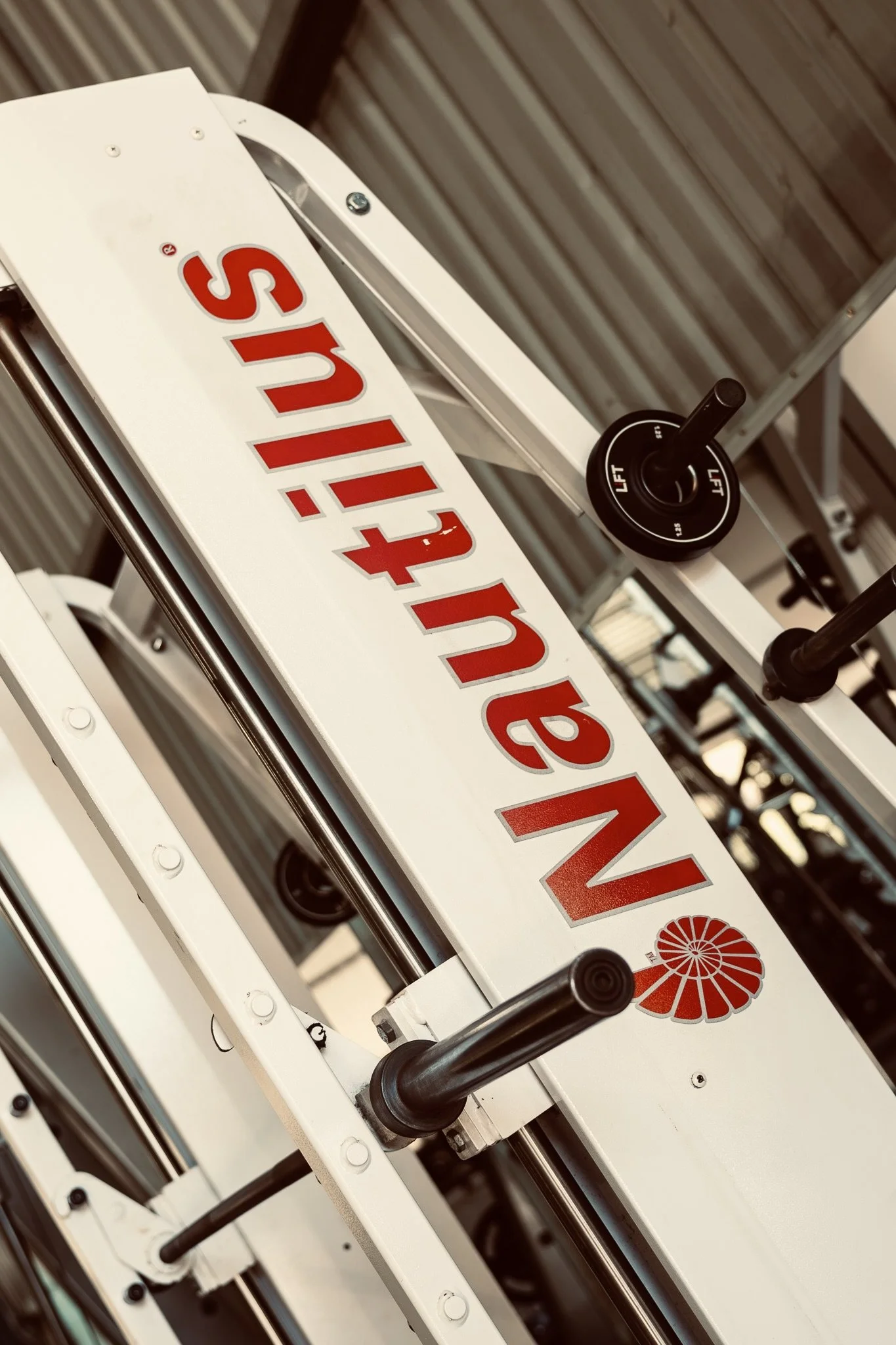 Close-up view of a piece of equipment with a white surface, red lettering spelling 'Sunlight', and a red sun logo. The equipment has black levers and metal rods, with a background of a ceiling with wooden panels.